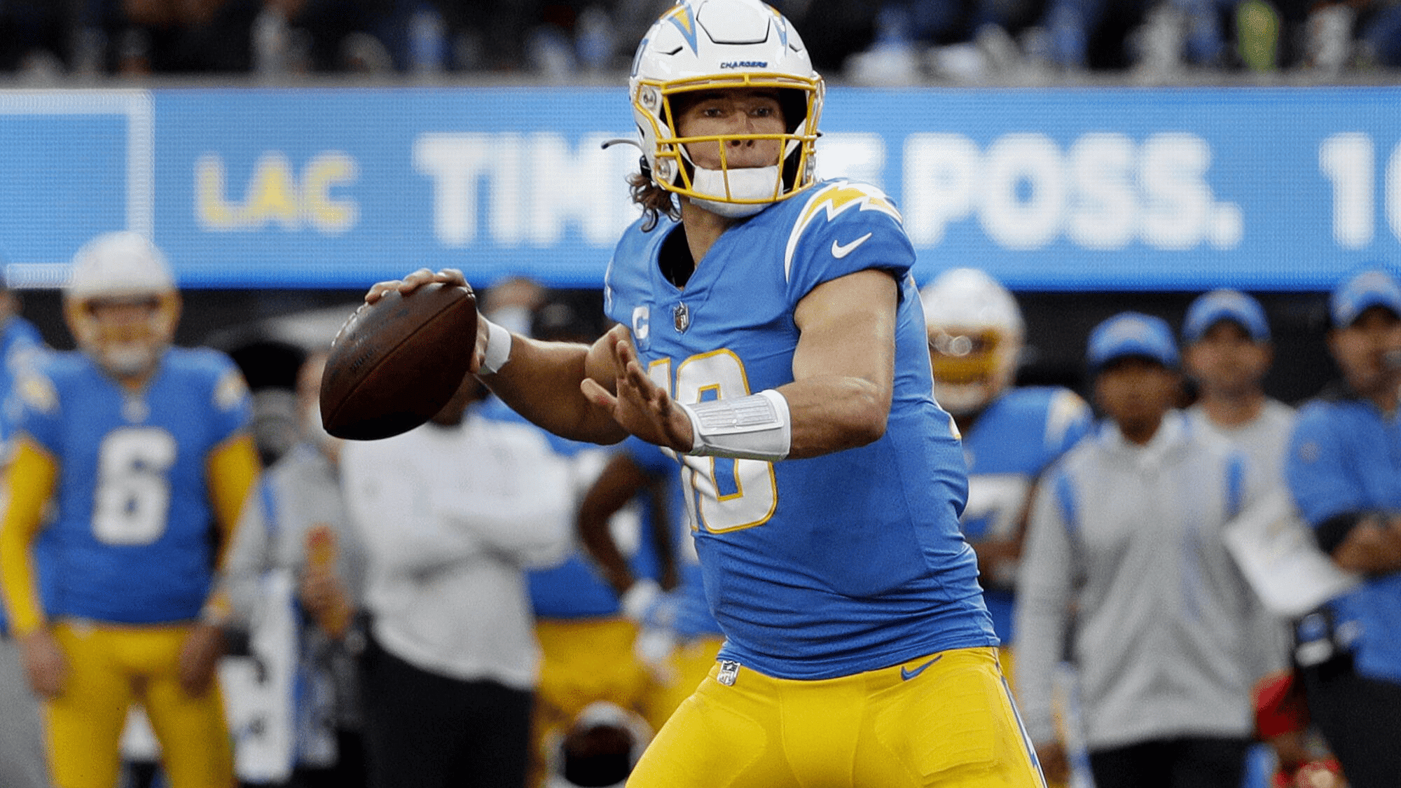 justin herbert in blue and yellow uniform focuses intently as he prepares to throw a football