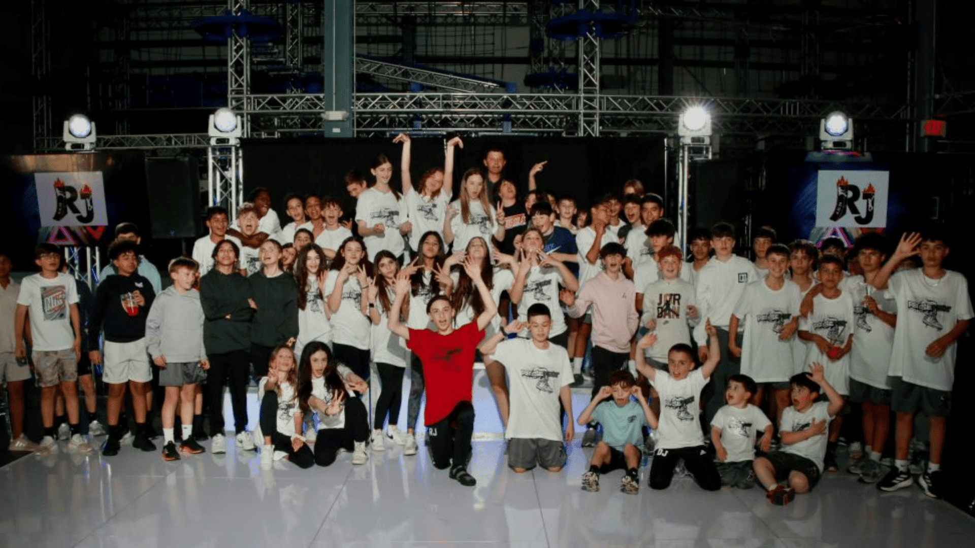 large group of kids posing together on a stage with lights at an indoor event at iron peak sports events