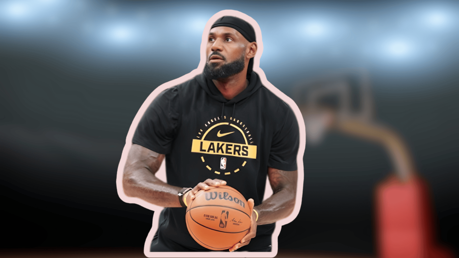 lebron james holding a basketball in Lakers hoodie focused before a shot with blurred court background and arena lights