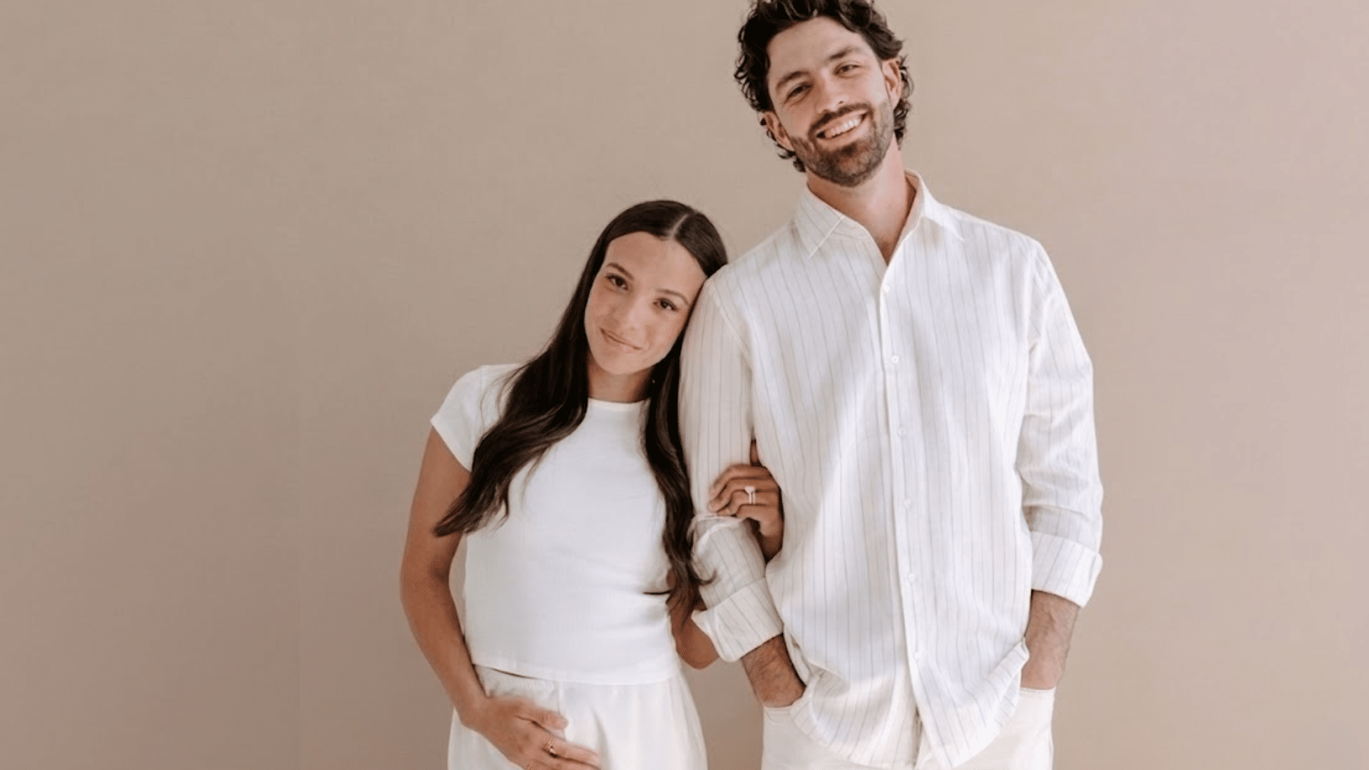 mallory and dansby swanson dressed in white stands together announcing pregnancy