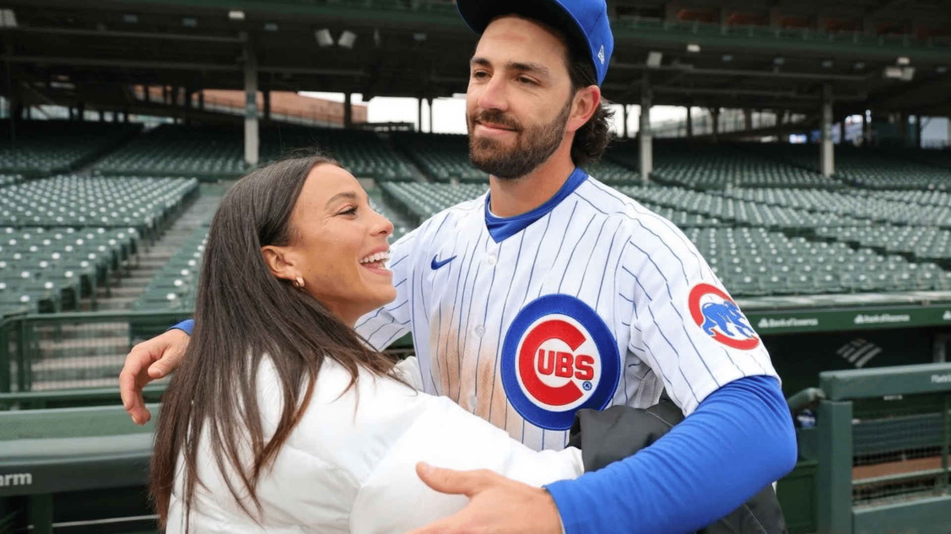 mallory and dansby swanson stand together at a stadium smiling and embracing while showing support and suggesting pregnancy