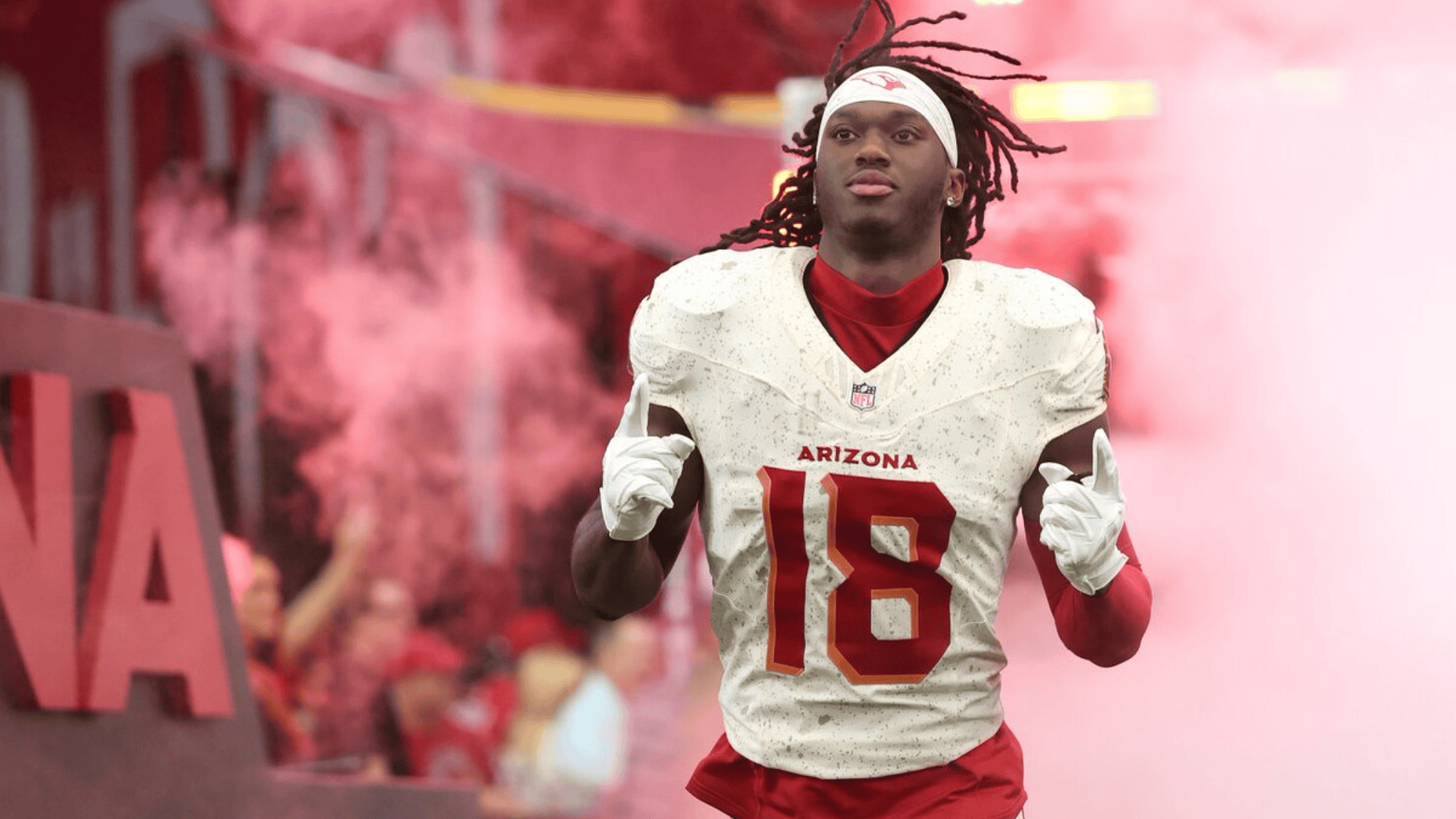 marvin harrison jr in white jersey marked arizona and number 18 jogs through pink smoke onto field