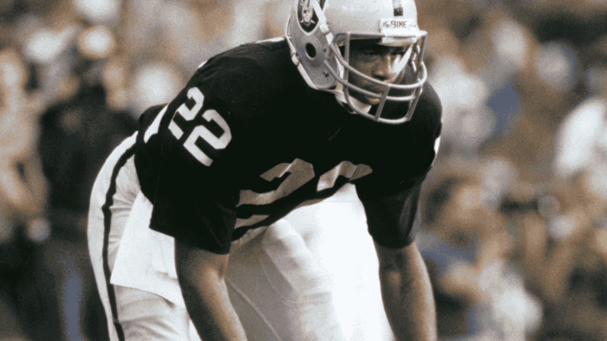 mike haynes in black Raiders uniform, number 22, crouched in a focused stance during a game