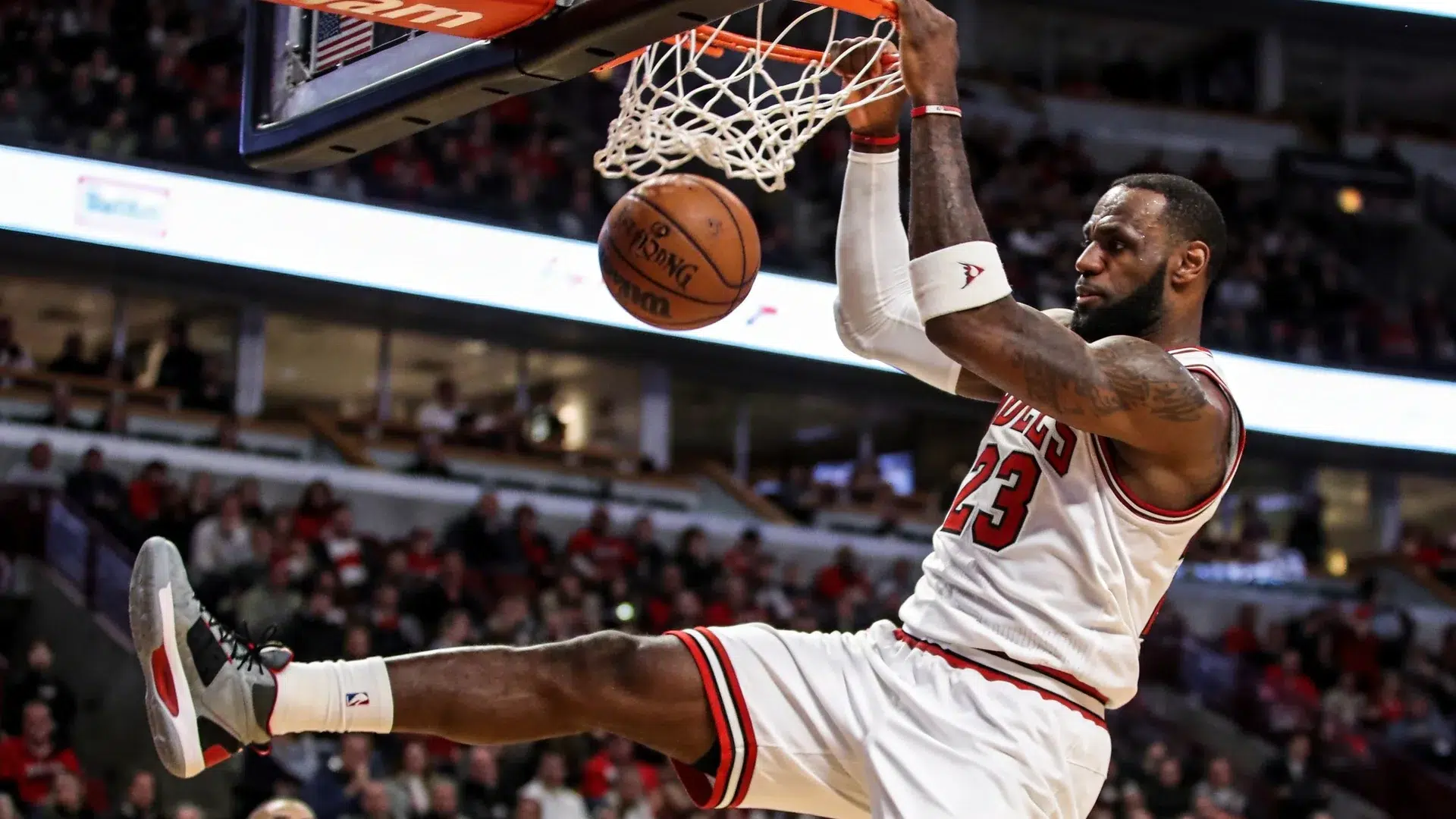 nba basketball player performing dunk during game with crowd in arena background
