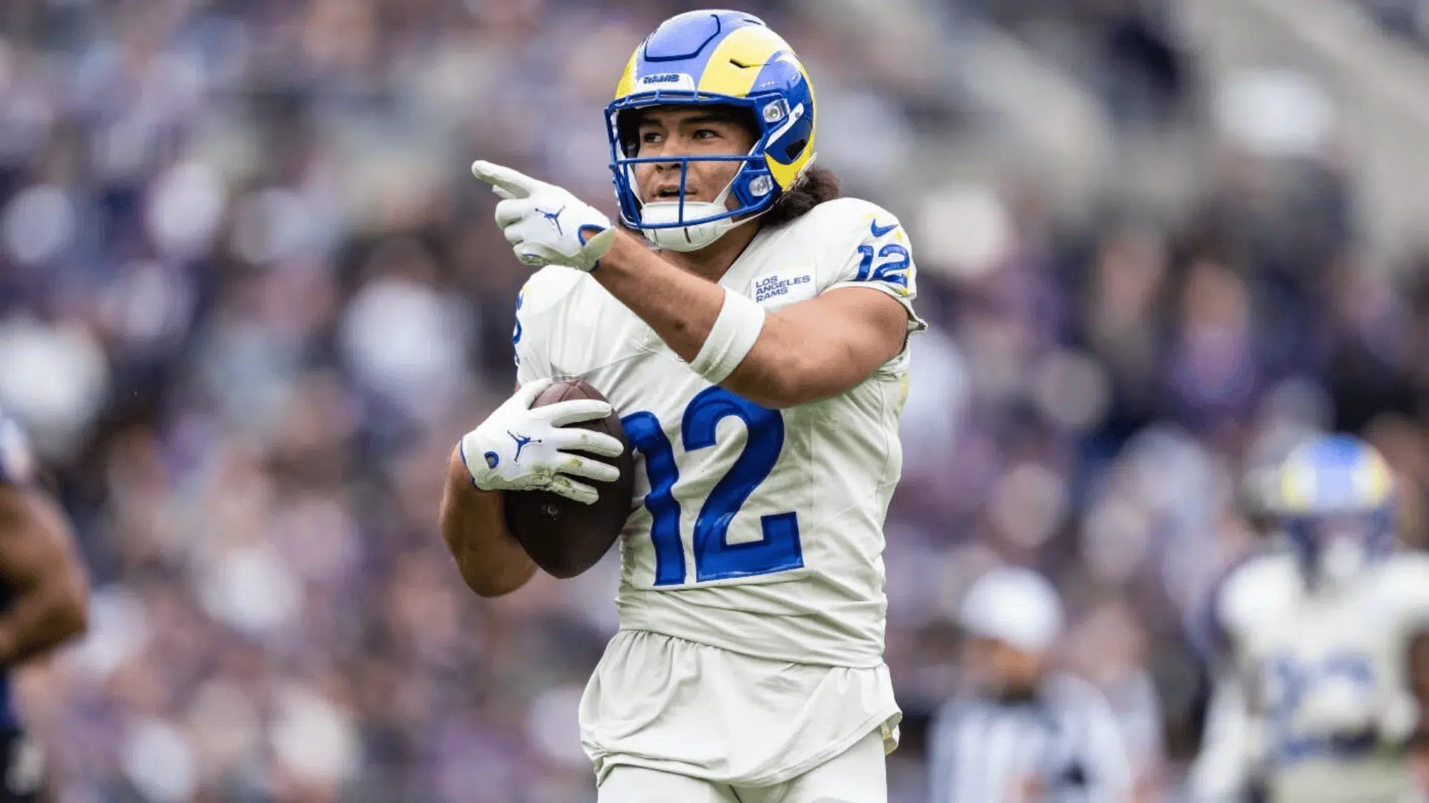 puka nacua in a white and blue jersey runs holding the ball pointing ahead