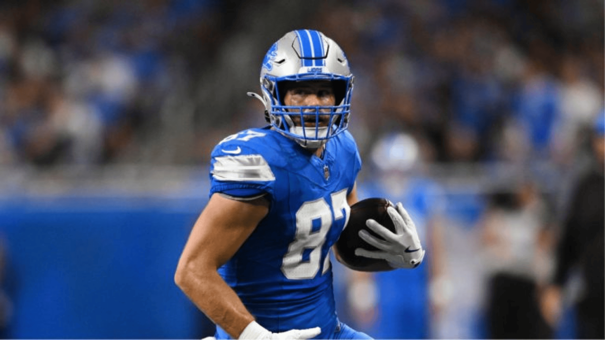 sam laporta in a blue and silver uniform runs determinedly with the ball