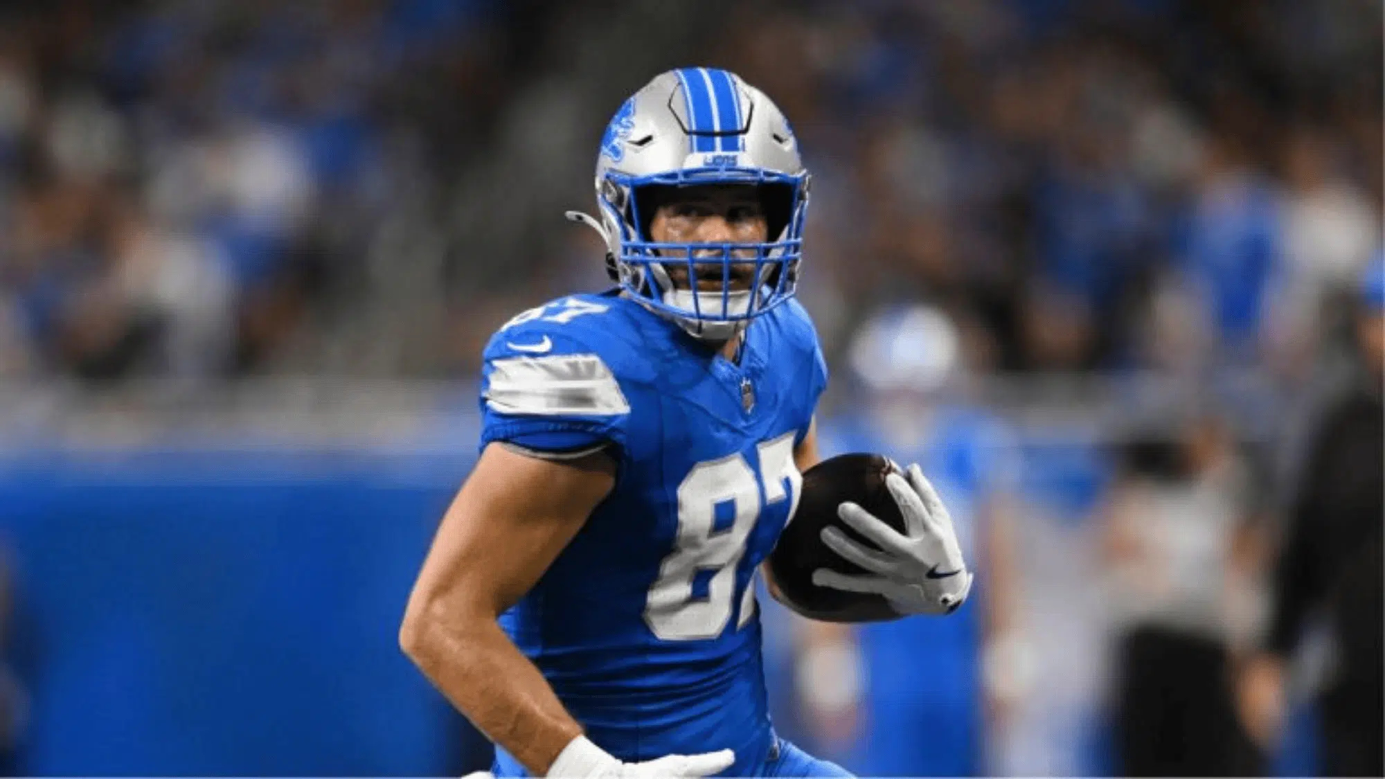 sam laporta in a blue and silver uniform runs determinedly with the ball