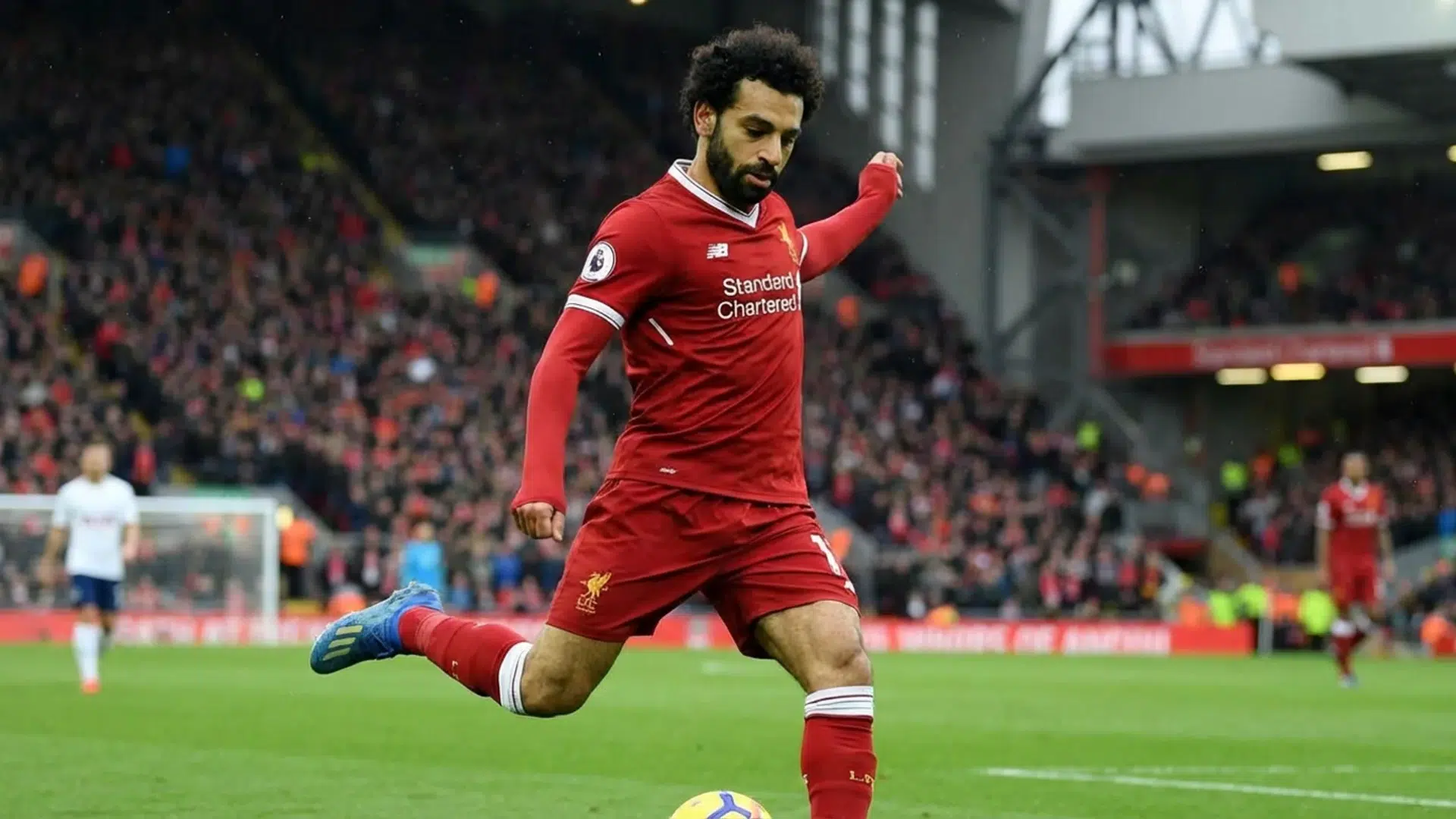 soccer player kicking ball during match with crowd in stadium watching action on the field
