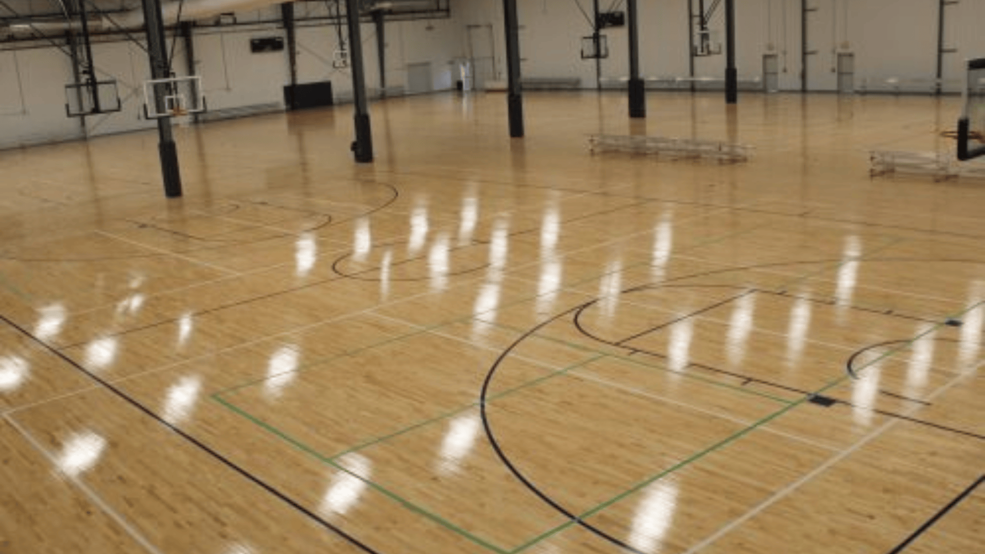 spacious indoor basketball court with gleaming wooden floors, multiple hoops, and overhead lights