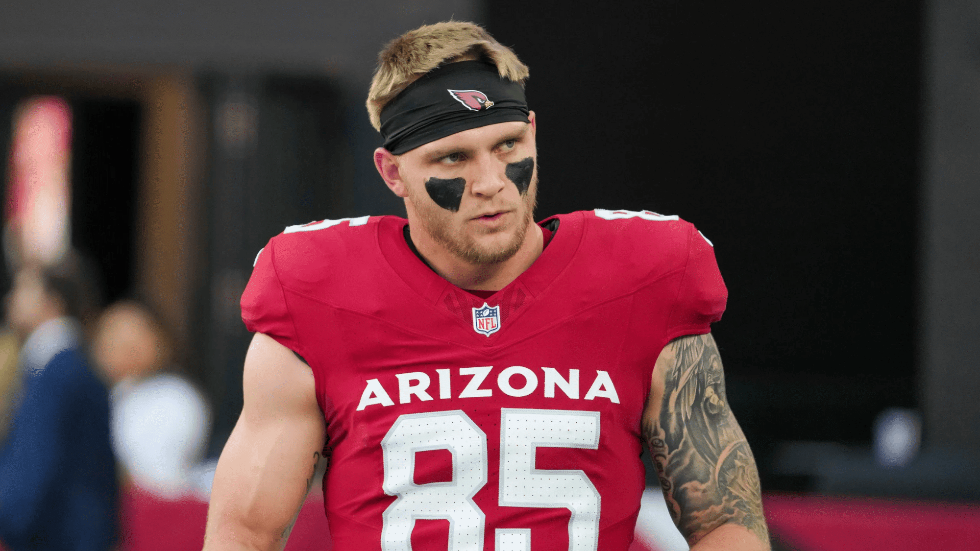 trey mcbride wearing a red arizona jersey with number 85 black eye paint and a headband looks focused and determined on the field