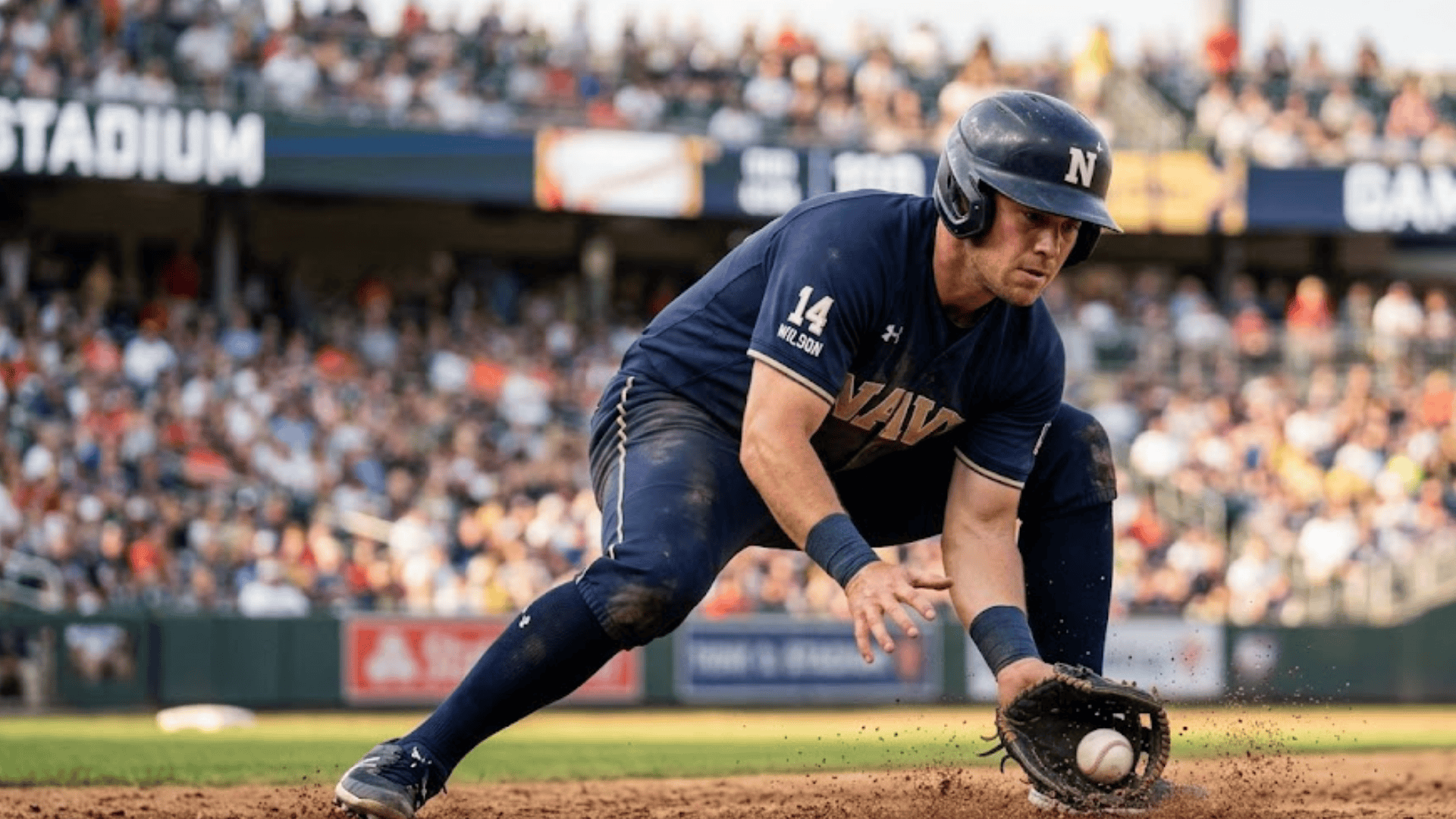 a baseball player in navy uniform bends low fielding ground ball with glove on dirt infield with crowd filled stadium in background