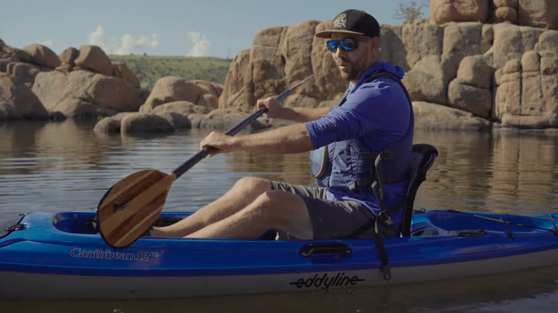 a person holds a kayak paddle with both hands spaced evenly and blades aligned correctly