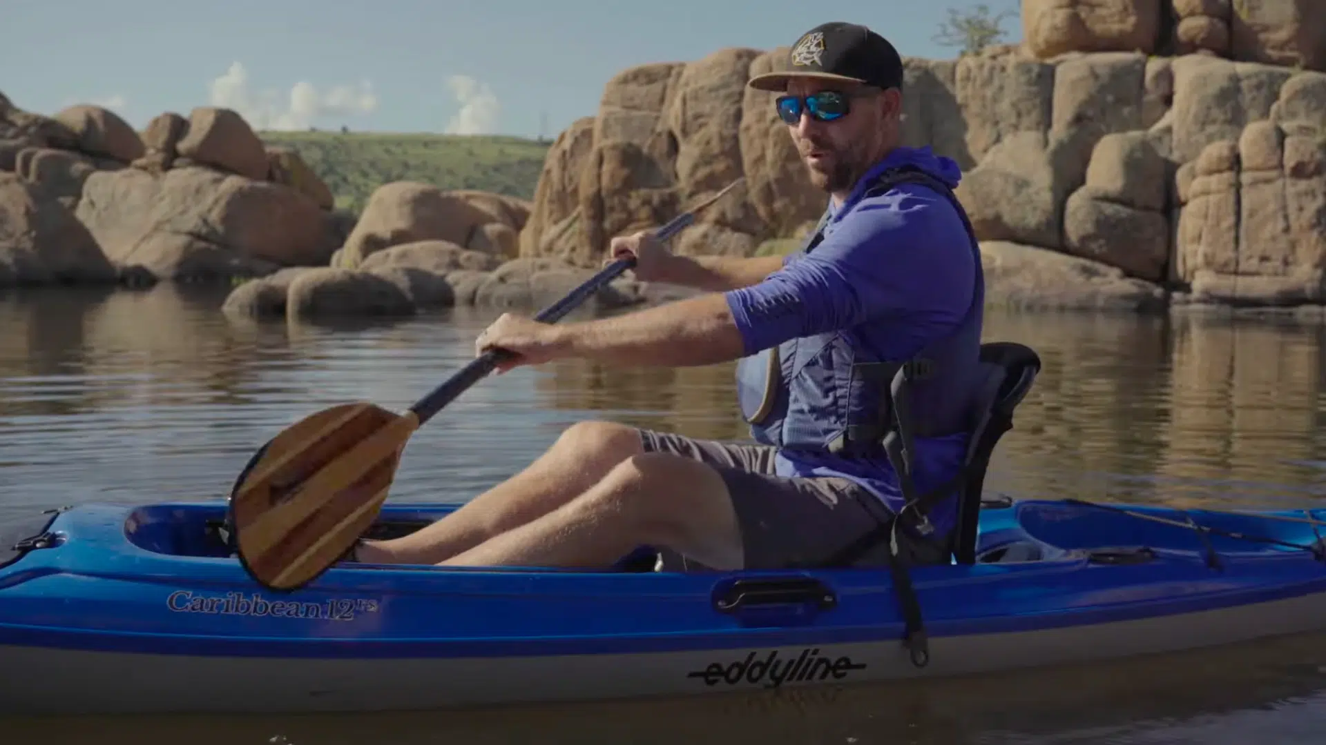 a person holds a kayak paddle with both hands spaced evenly and blades aligned correctly