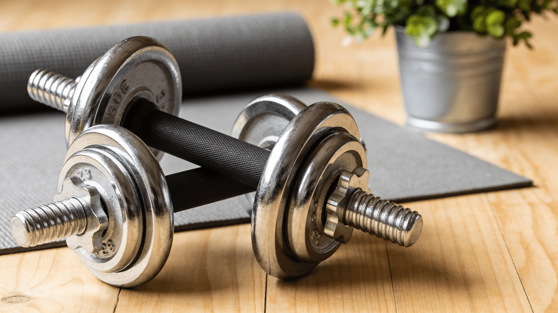 adjustable metal dumbbells resting on yoga mat indoors
