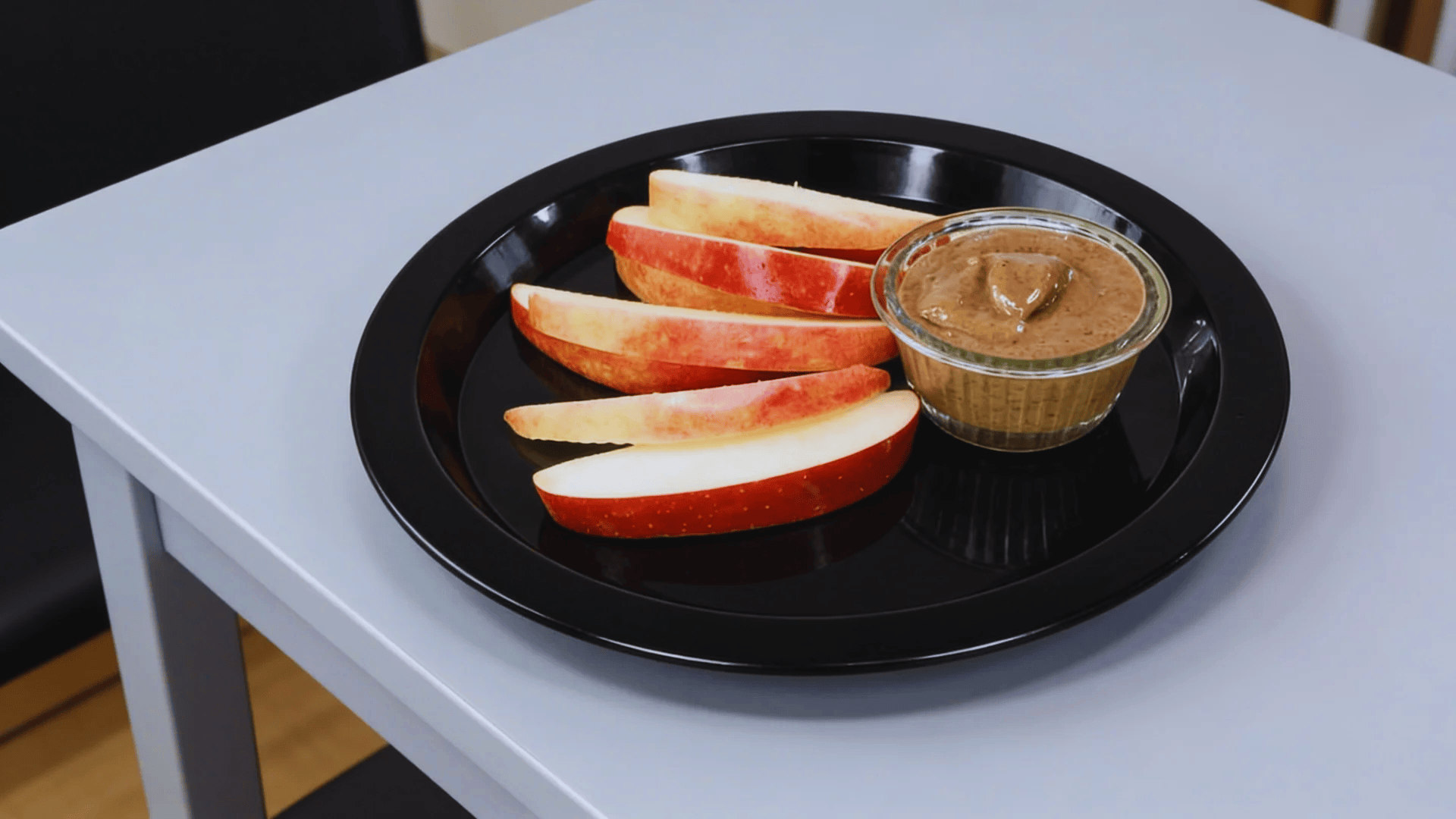 apple slices with peanut butter dip on a black plate