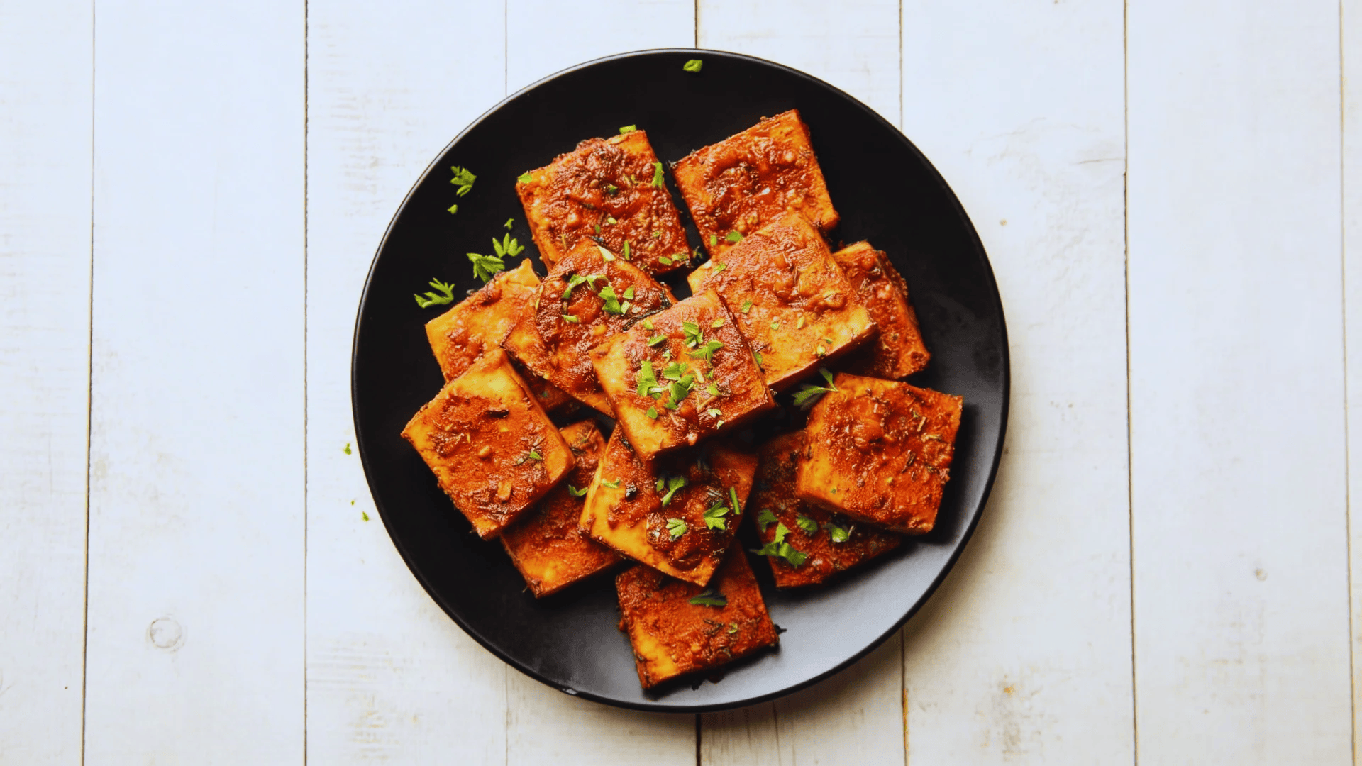 baked tofu cubes with seasoning on a black plate