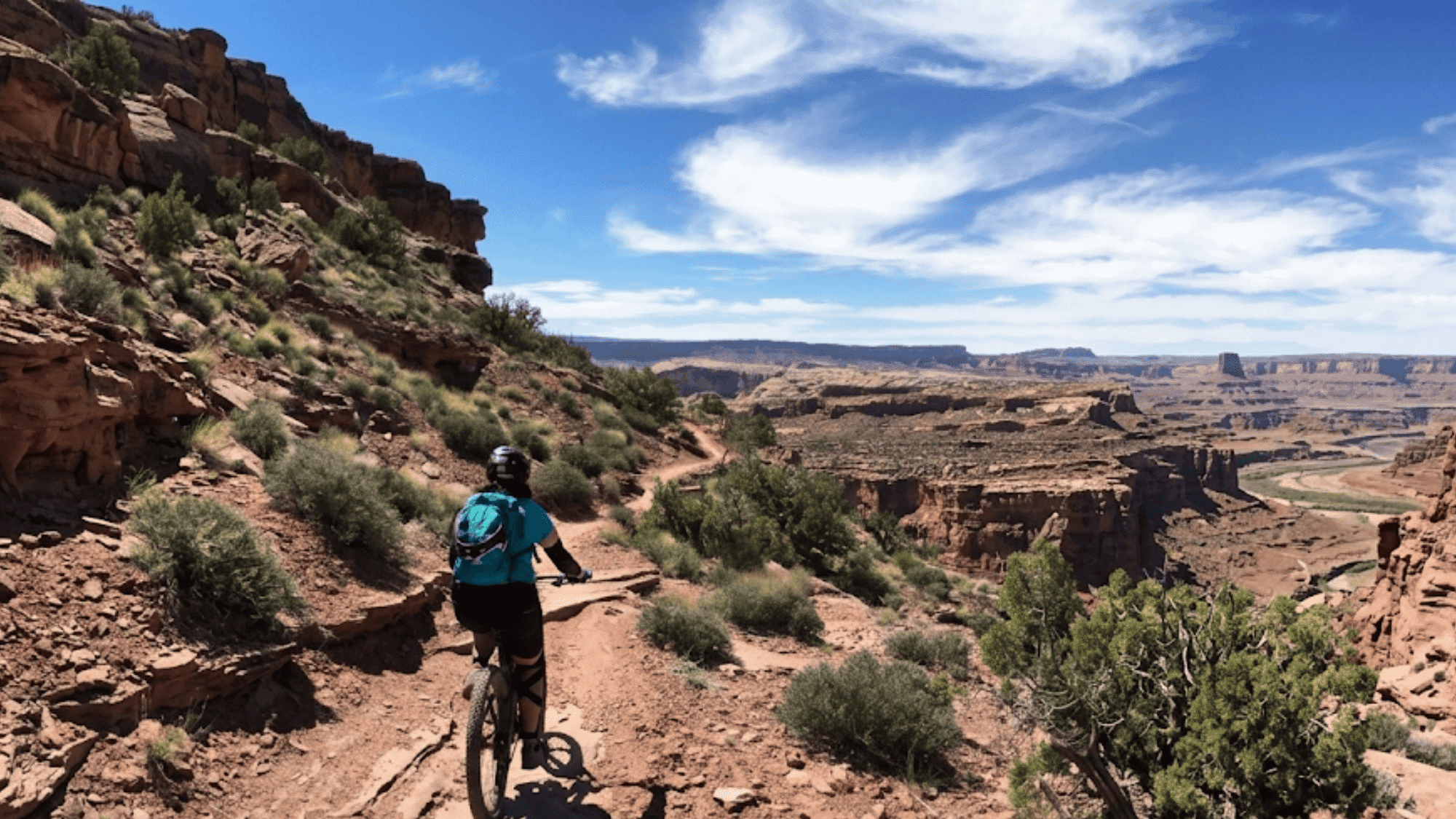 biker riding on a dirt trail with canyon view in moab utah whole enchilada trail