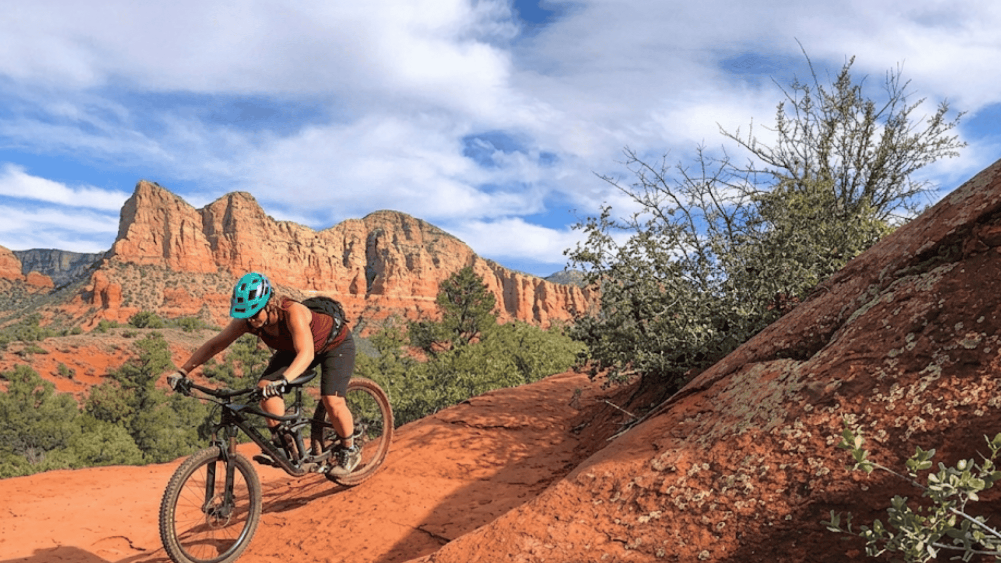 biker riding on red rock trail in arizona sedona trails with desert mountains and clear sky