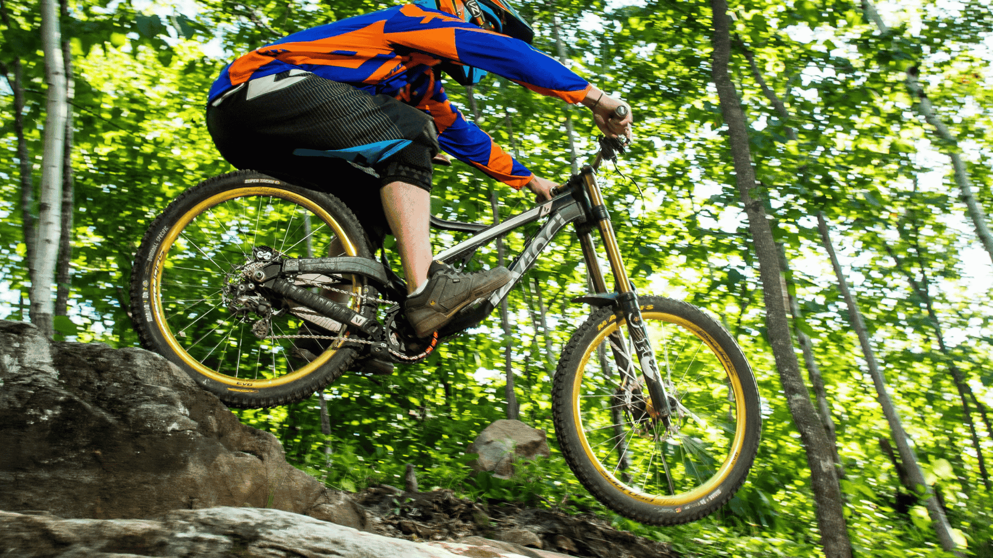 biker riding over rocks in minnesota duluth traverse trail through forest with trees and dirt path