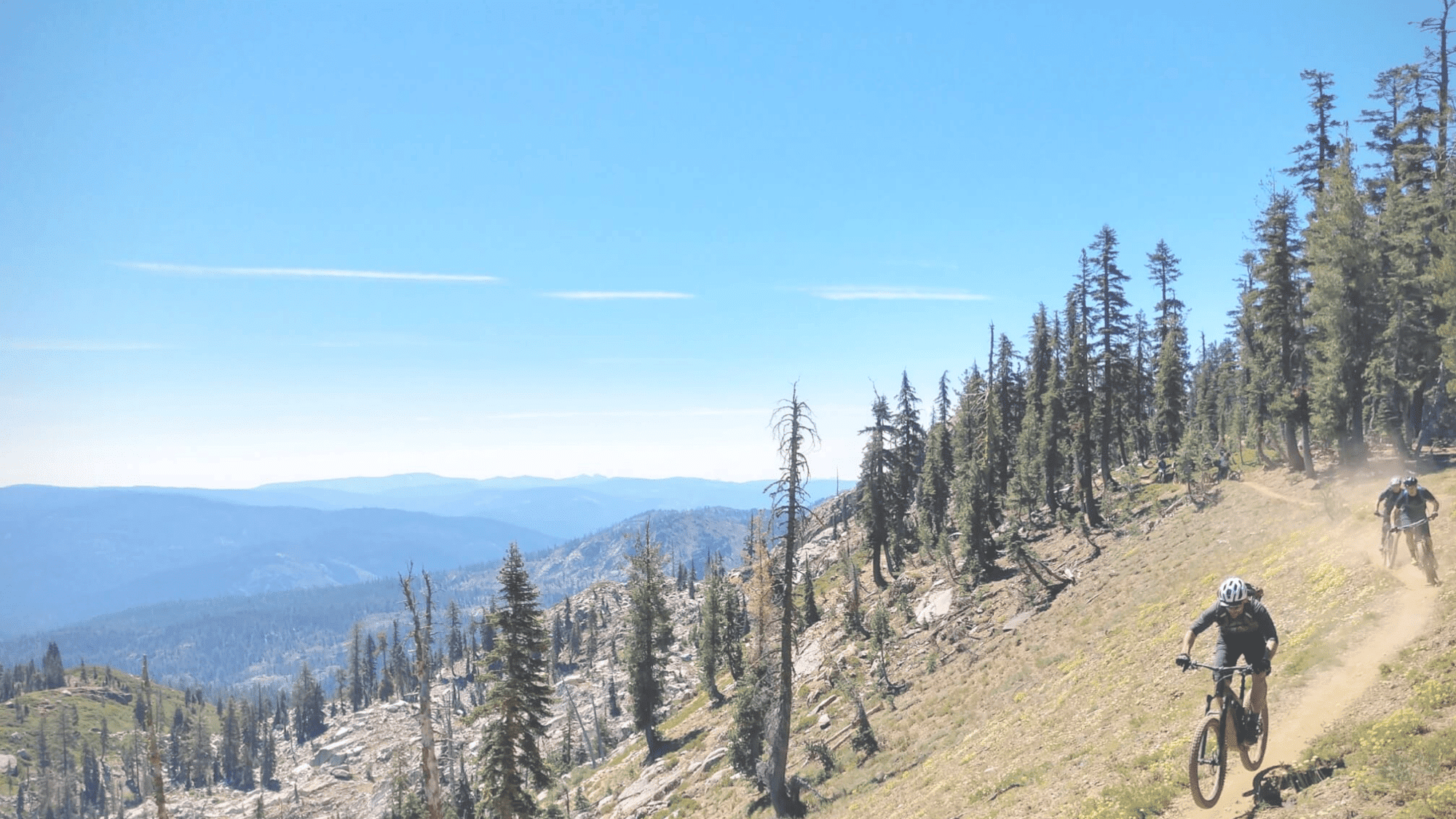 bikers riding downhill trail in california downieville with mountain views and trees around