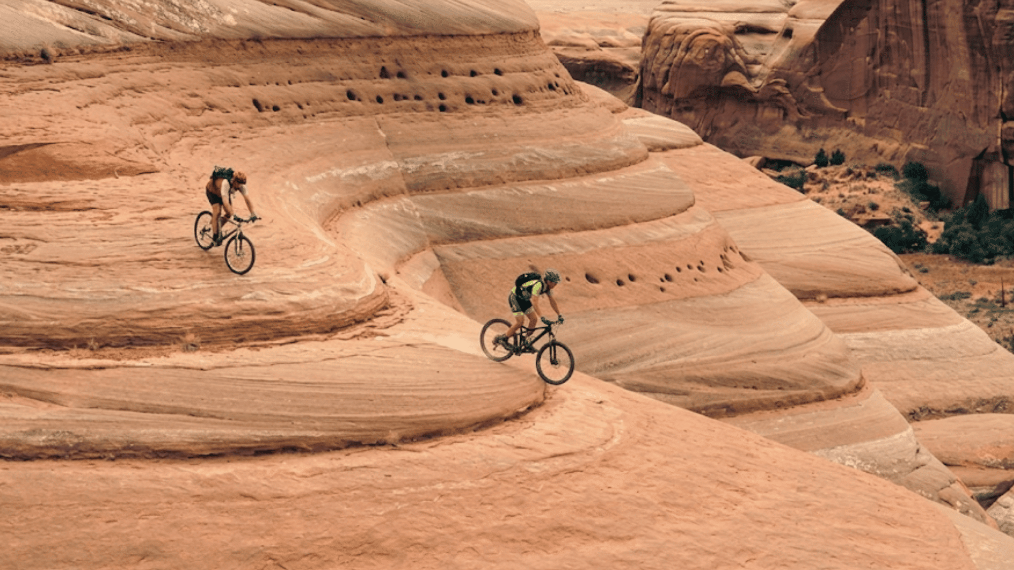 bikers riding on smooth rock trail in moab utah slickrock trail with wide desert view around