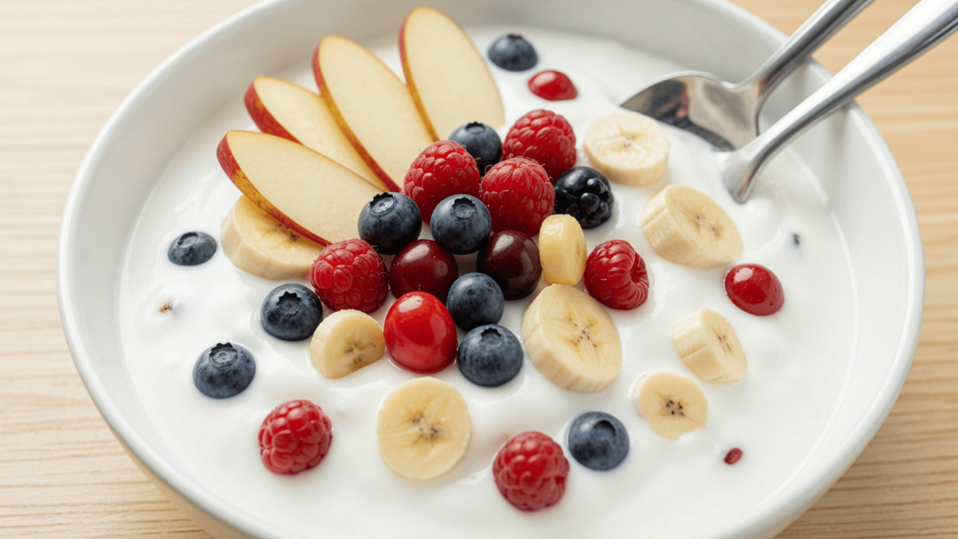 bowl of yogurt with banana berries and apple slices as fresh post workout meal
