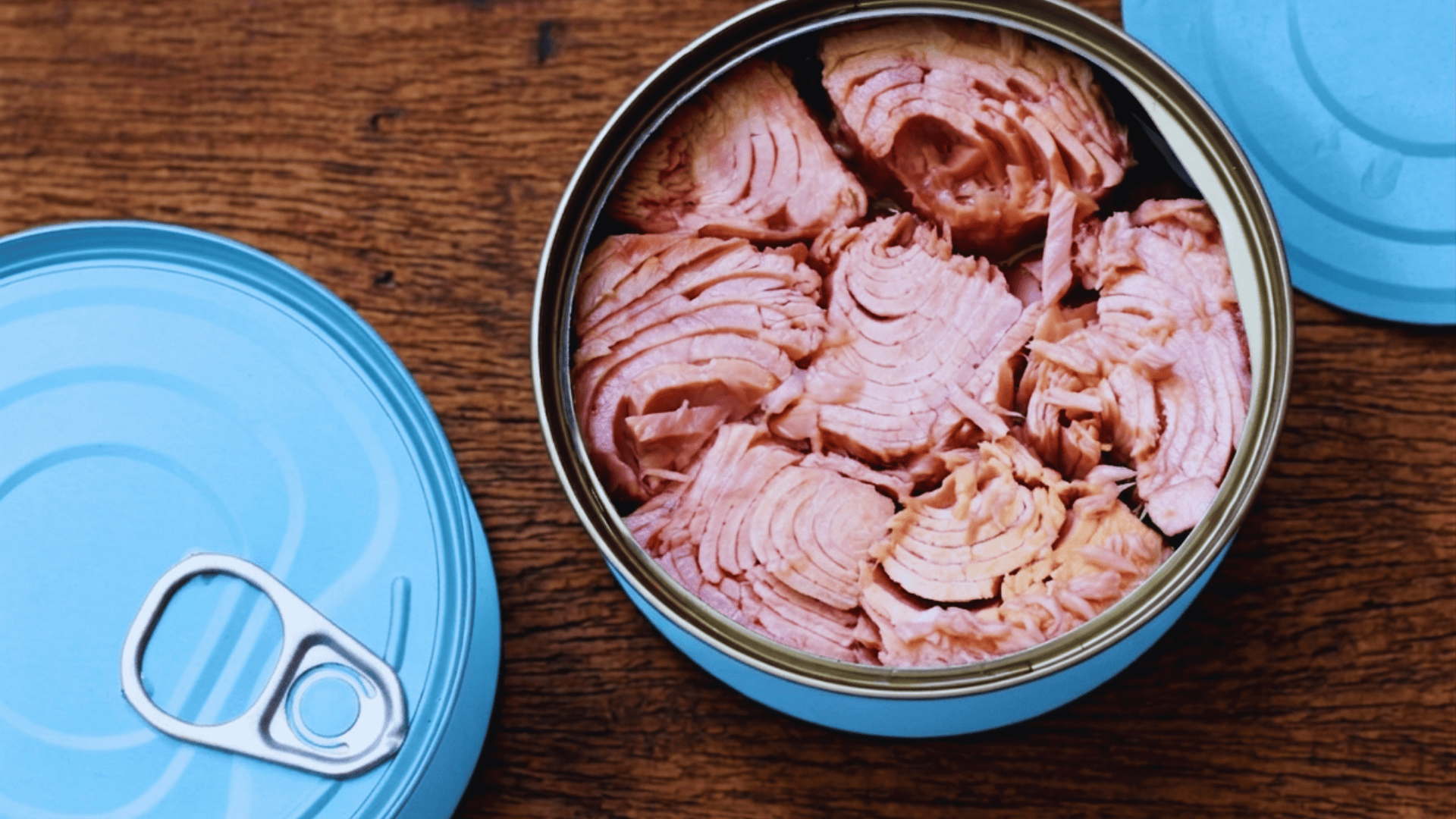canned tuna chunks in an open tin on a wooden surface