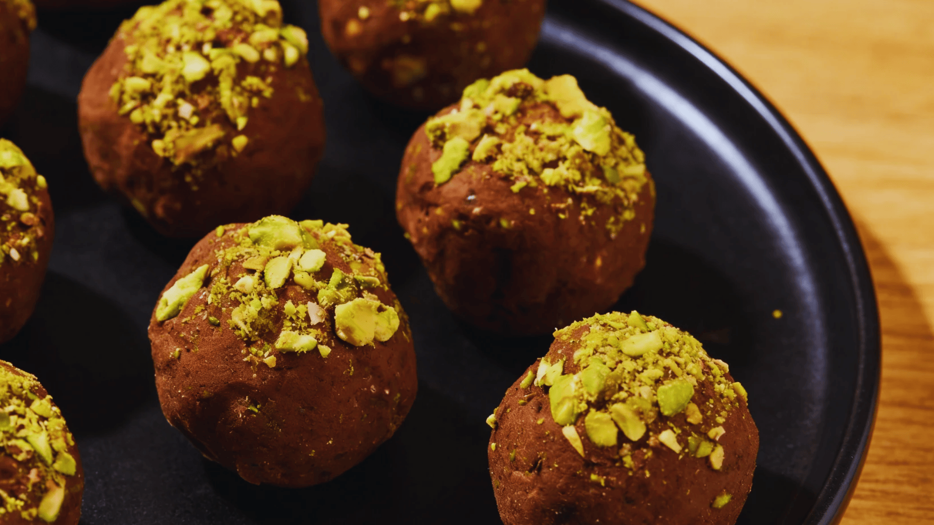 cchocolate energy bites with chopped pistachios on black plate