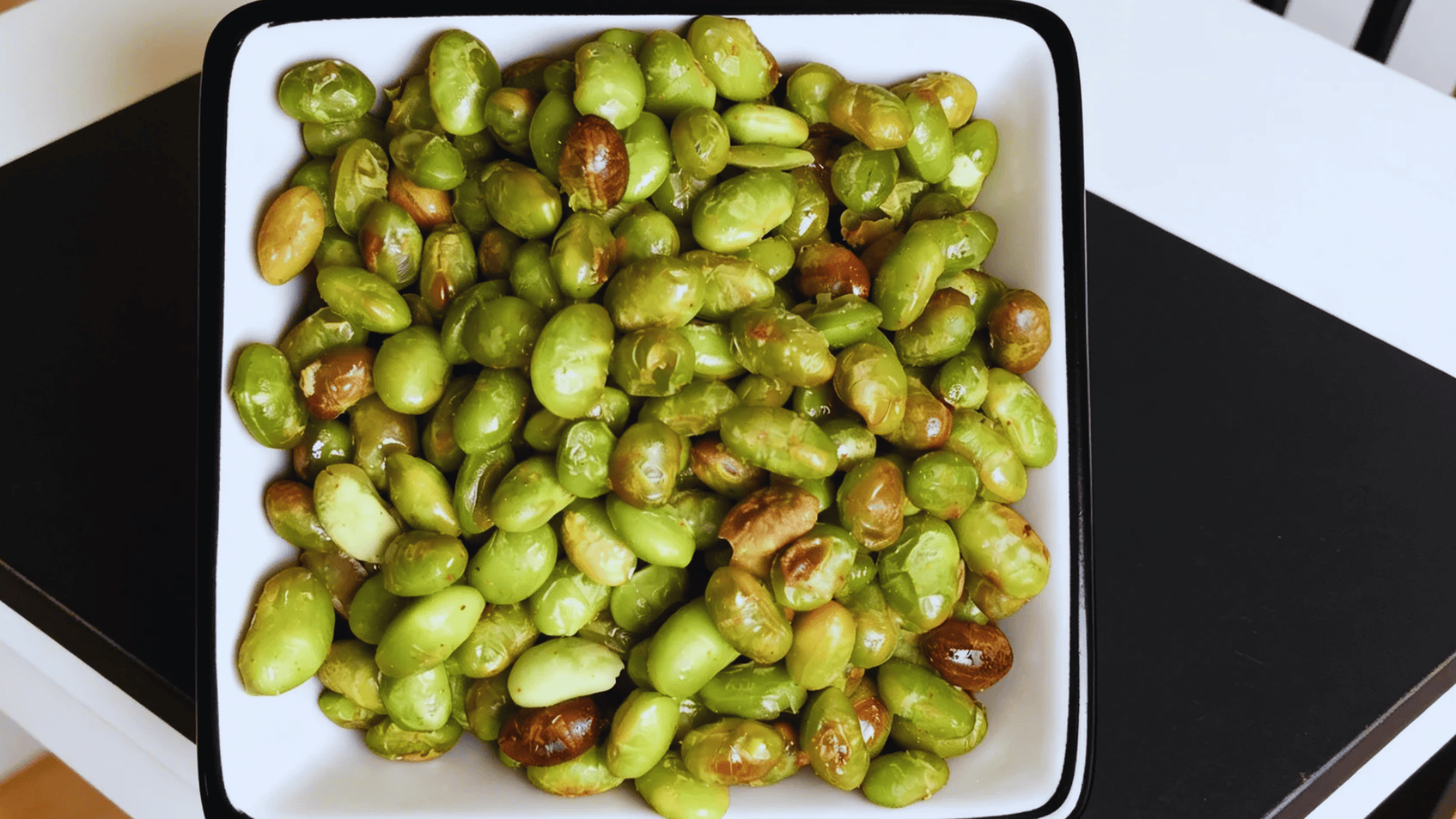 edamame beans in a square white bowl on a table