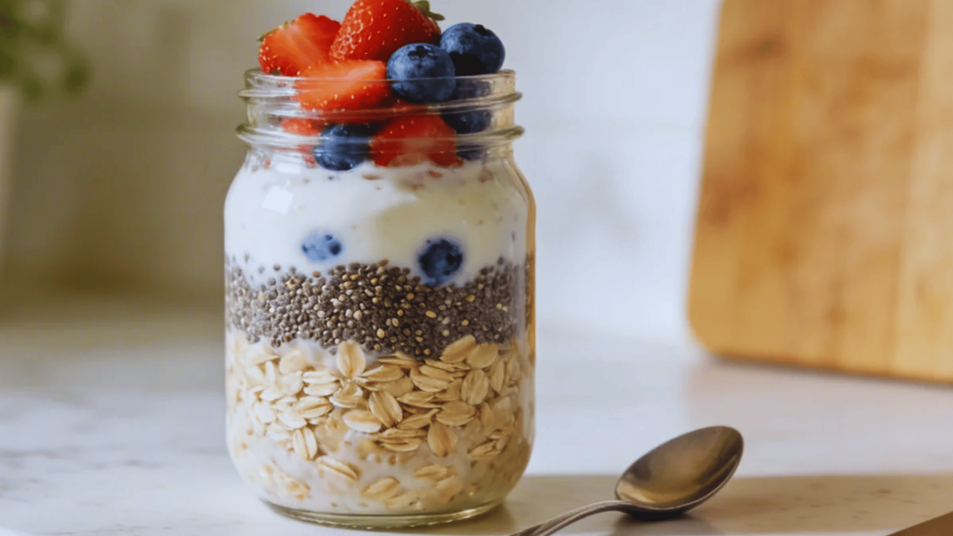 layered chia overnight oats with berries in jar on kitchen counter