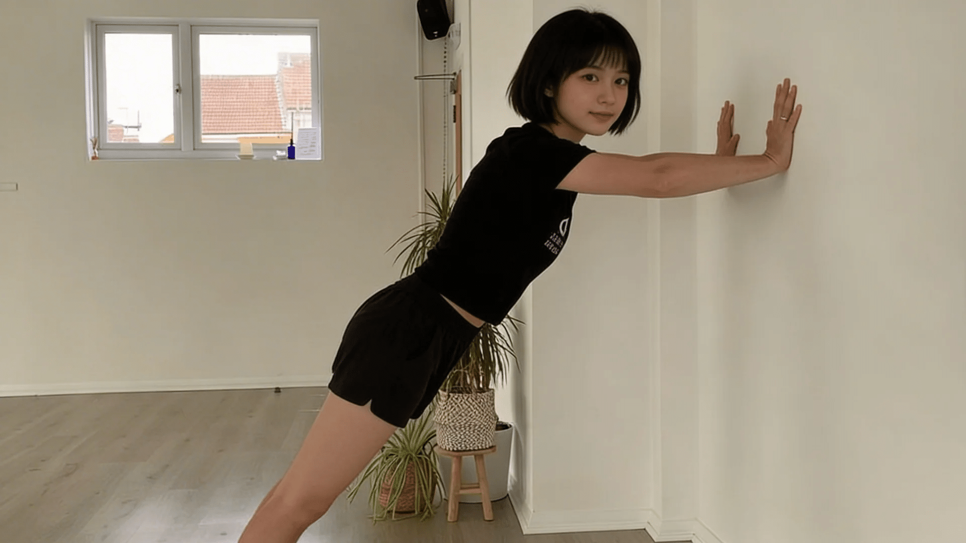 leaning forward with hands on wall performing calf raise exercise in home workout space
