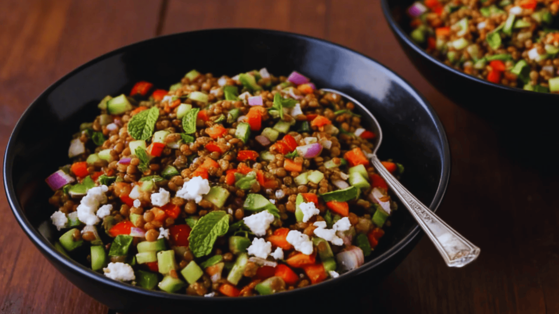 lentil salad with cucumber peppers herbs and feta in black bowl