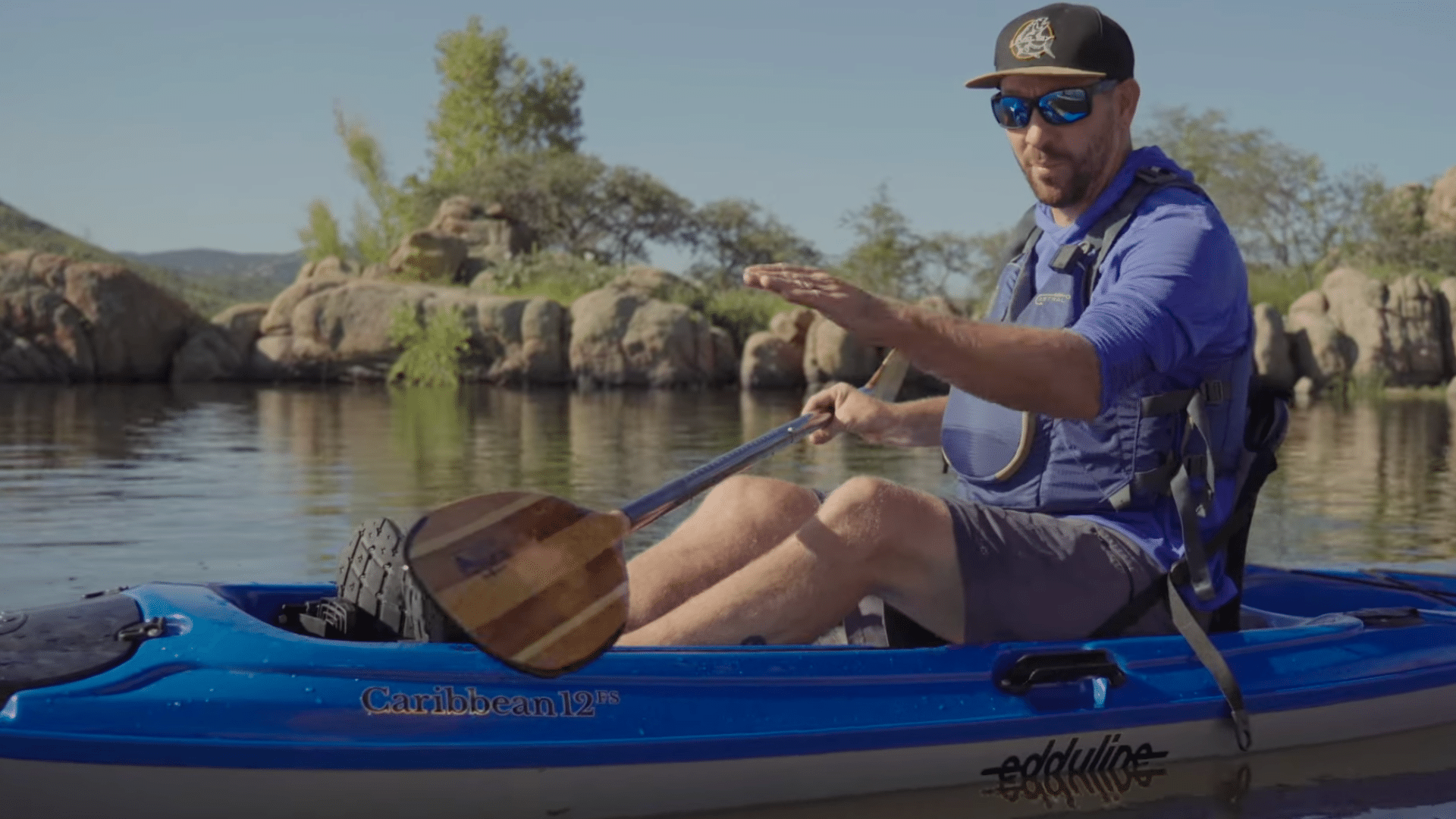 paddles a kayak using a sweep stroke to turn and control direction smoothly while maintaining balance