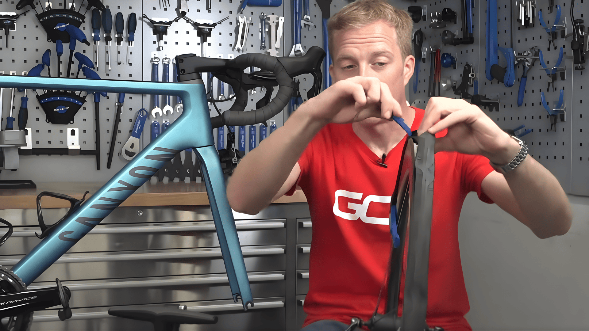 person using blue tire levers to remove bike tire from rim demonstrating how to change bike tire close up hands and wheel