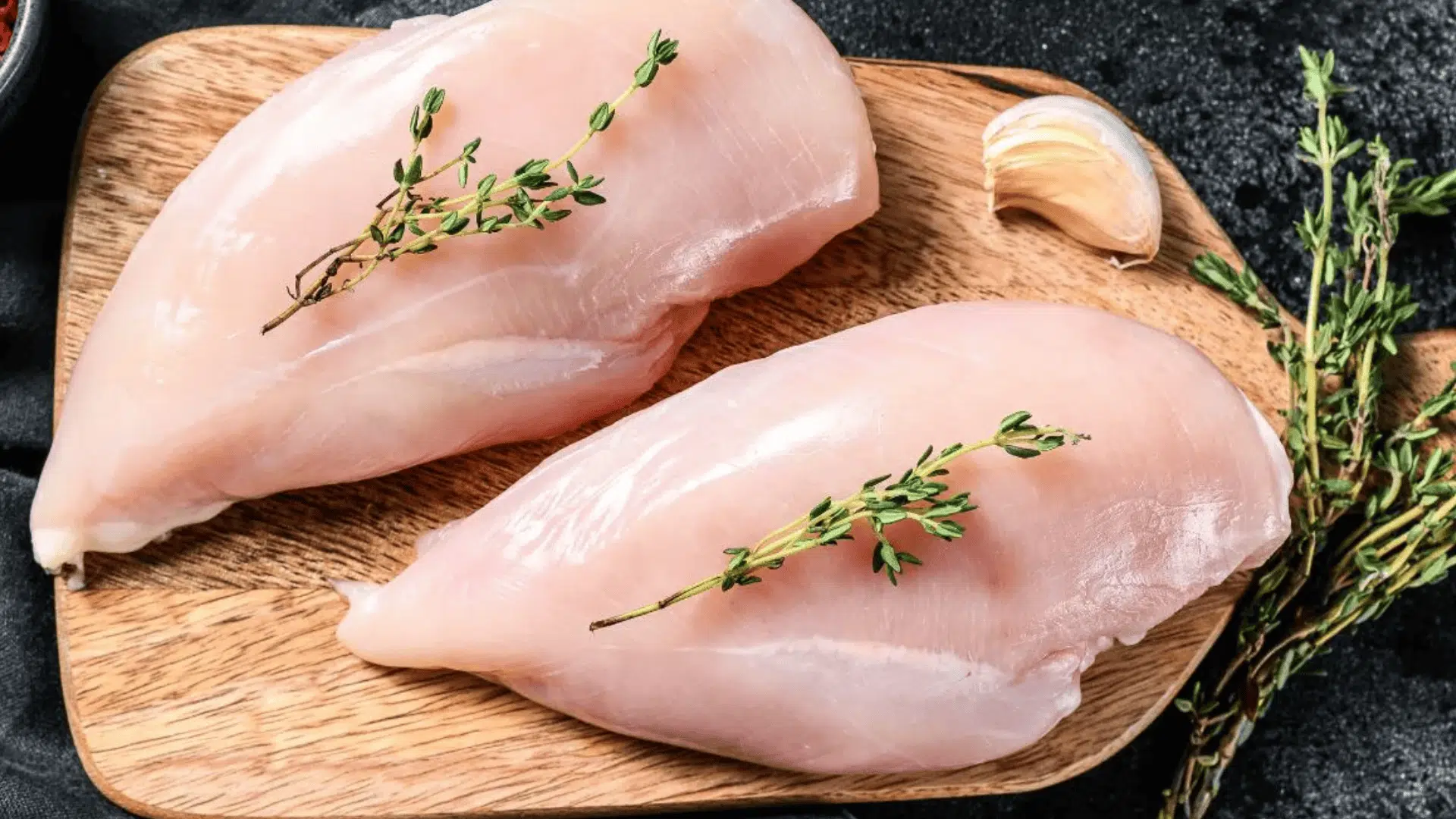 raw chicken breast fillets on wooden board with herbs and garlic beside them what is the best recovery food