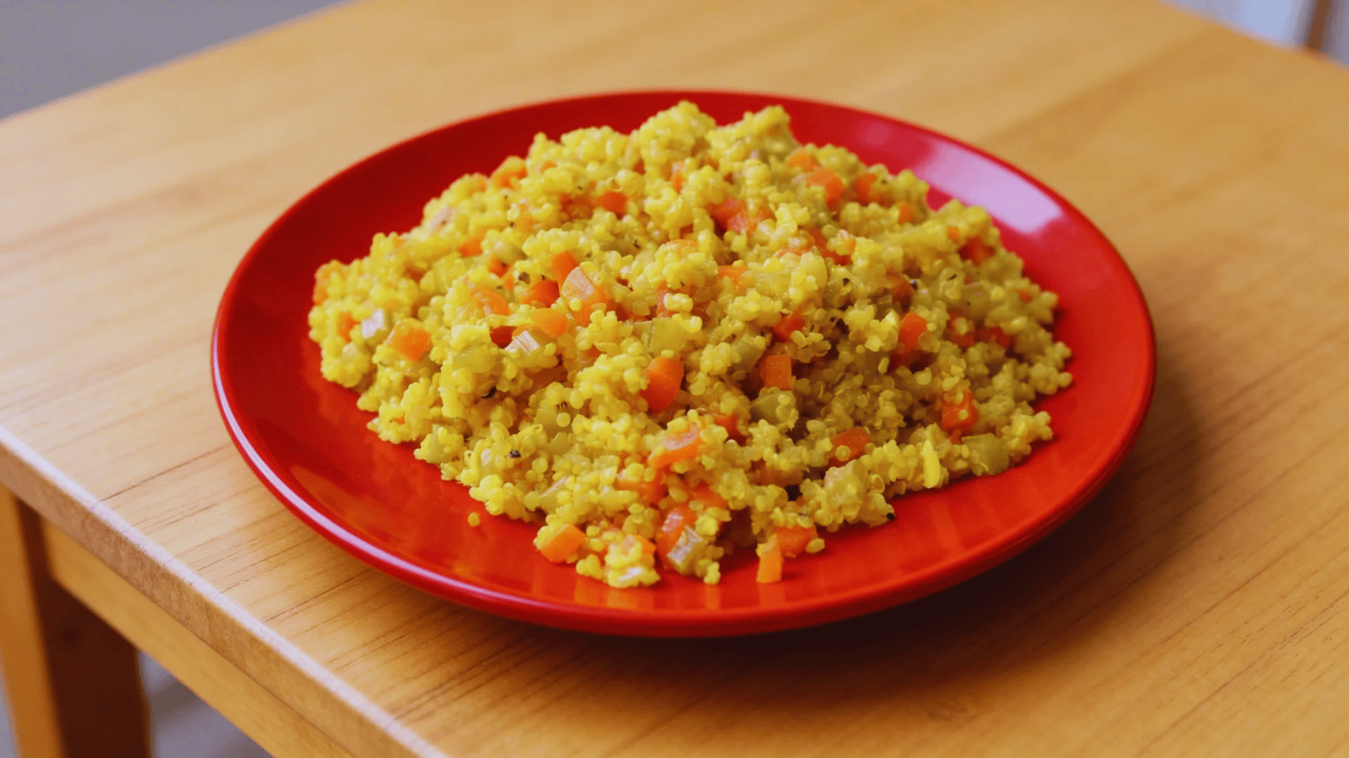 vegetable quinoa on red plate with carrots and herbs
