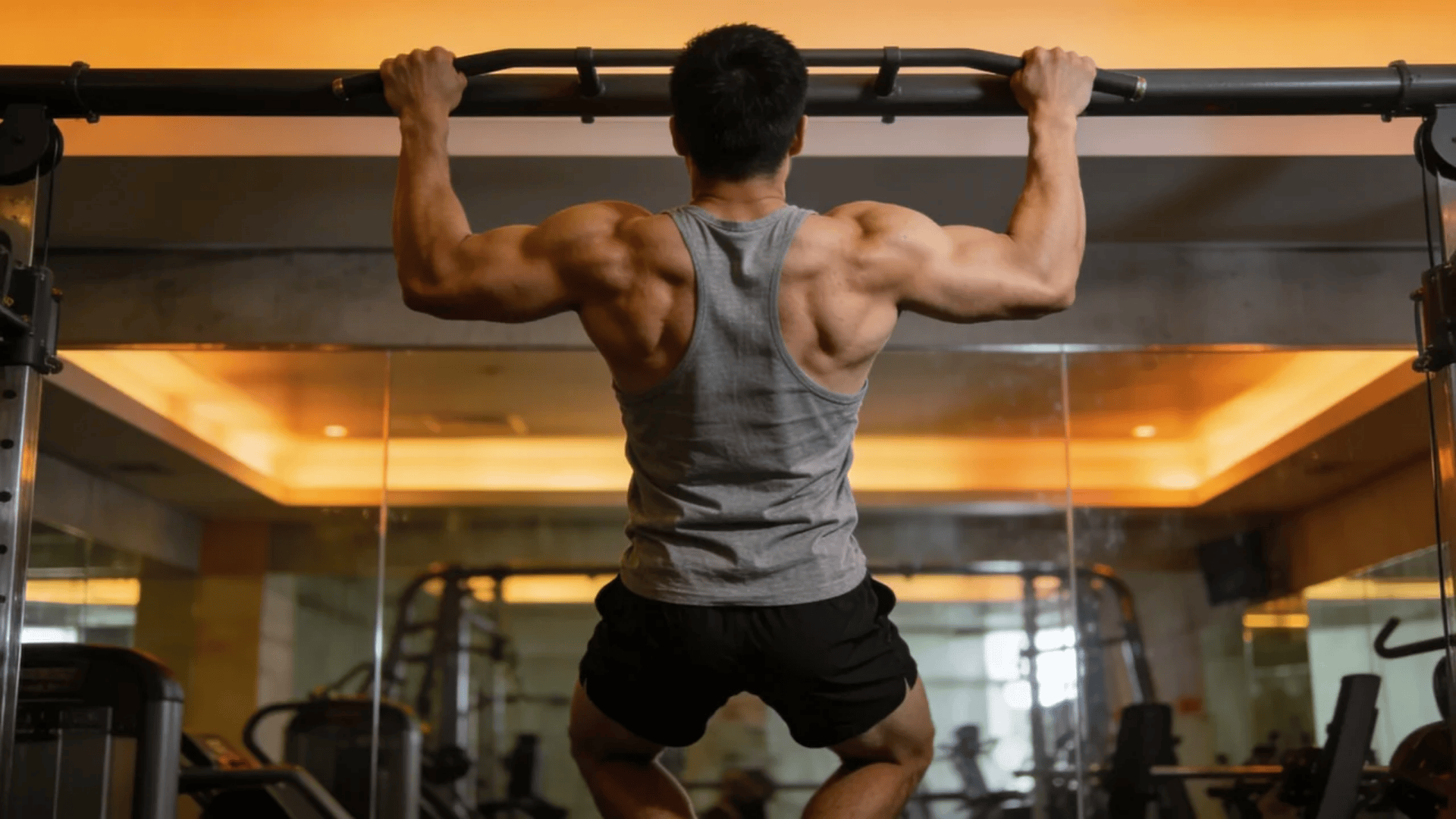 what muscles do pull ups work man performing pull up showing strong back and arm muscles in gym