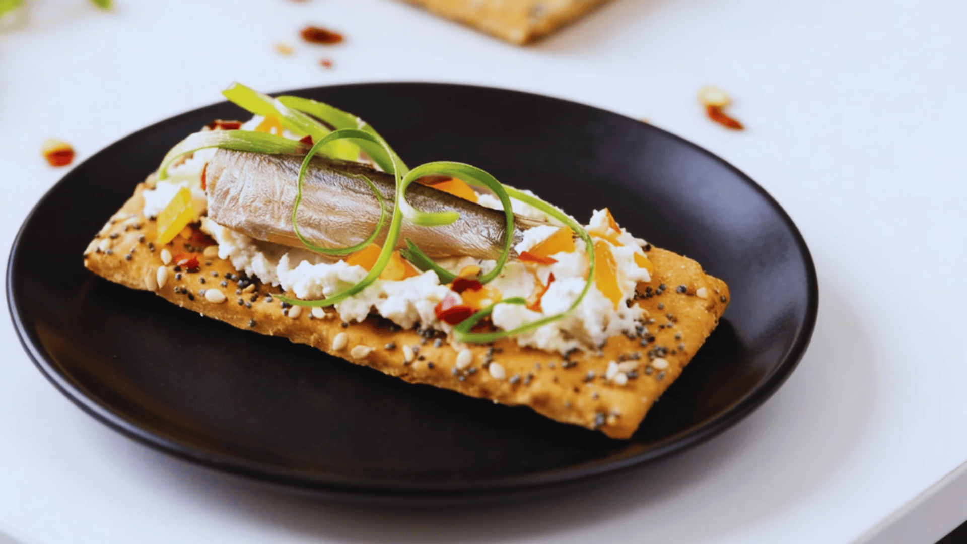 whole grain cracker with cheese and fish topped with greens