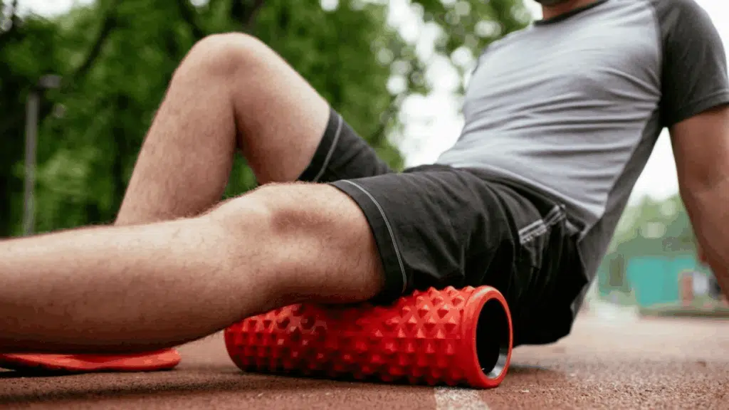 athlete using a foam roller on leg muscles after exercise to reduce soreness and improve recovery
