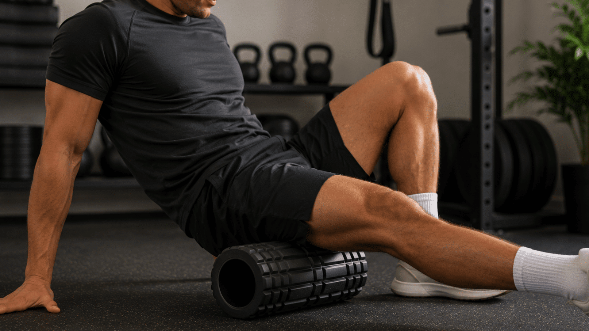 athlete using a foam roller on thigh muscles during a recovery workout session in a modern gym