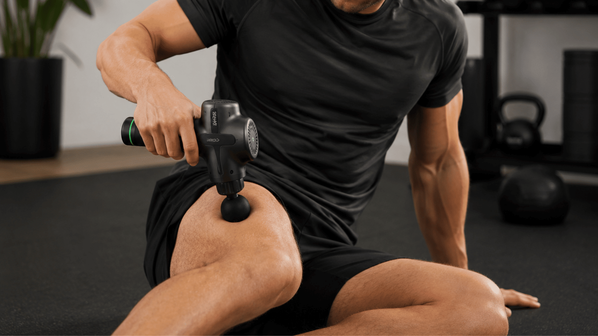 athlete using a massage gun on leg muscles during recovery session in a modern home gym