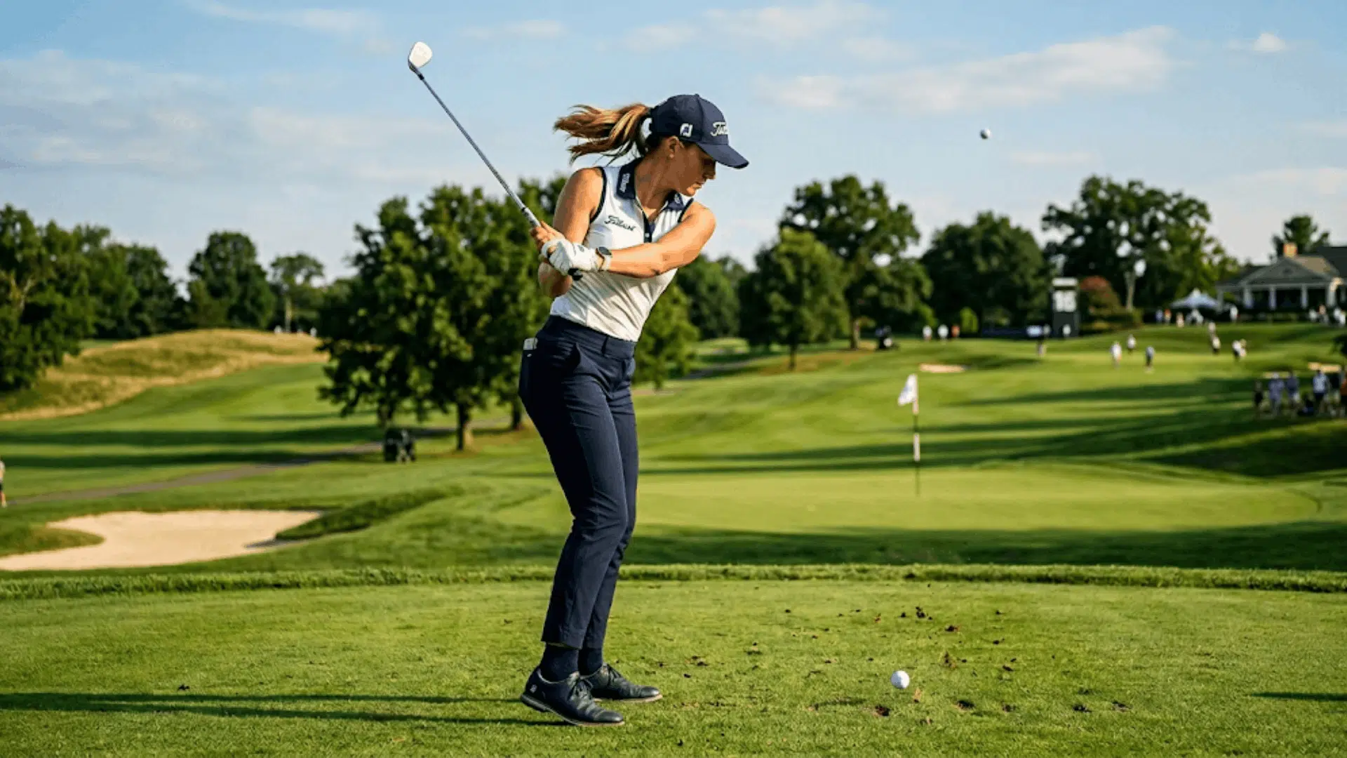 female golfer practicing a clean iron shot on a beautiful green golf course