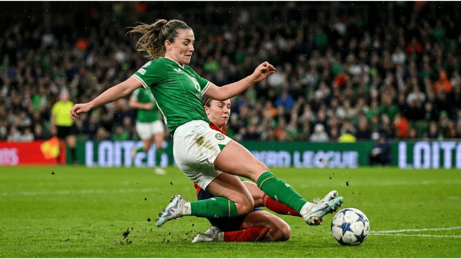 female soccer player kicking the ball while another player slides for a tackle during an international match