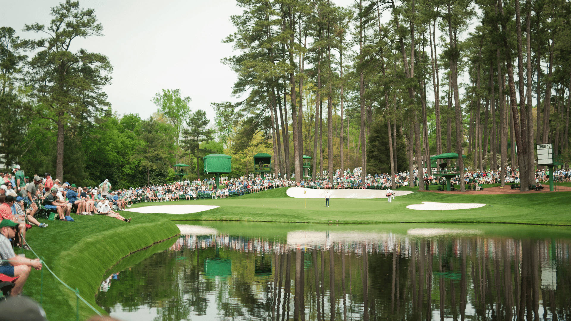 golf fans watching players compete beside the water hazard at augusta national during the masters tournament