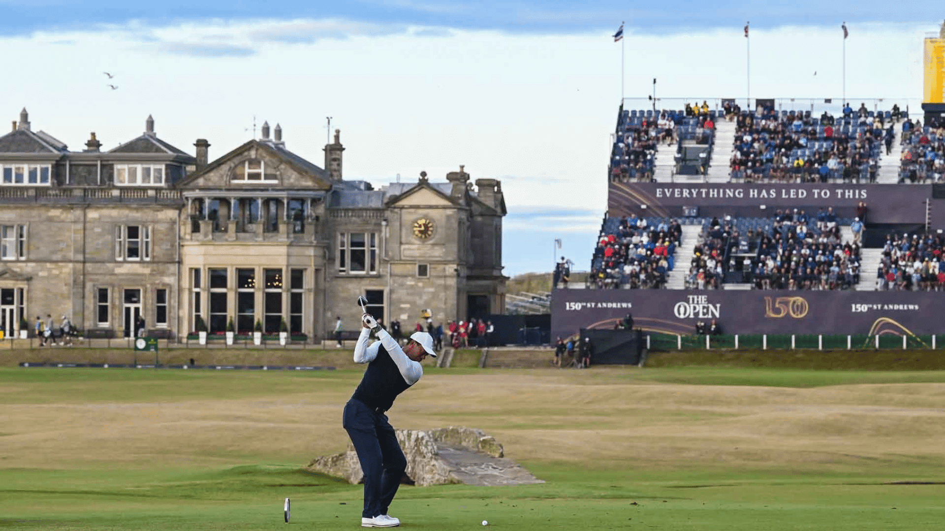 golfer taking a tee shot during the open championship at st andrews with spectators in the stands