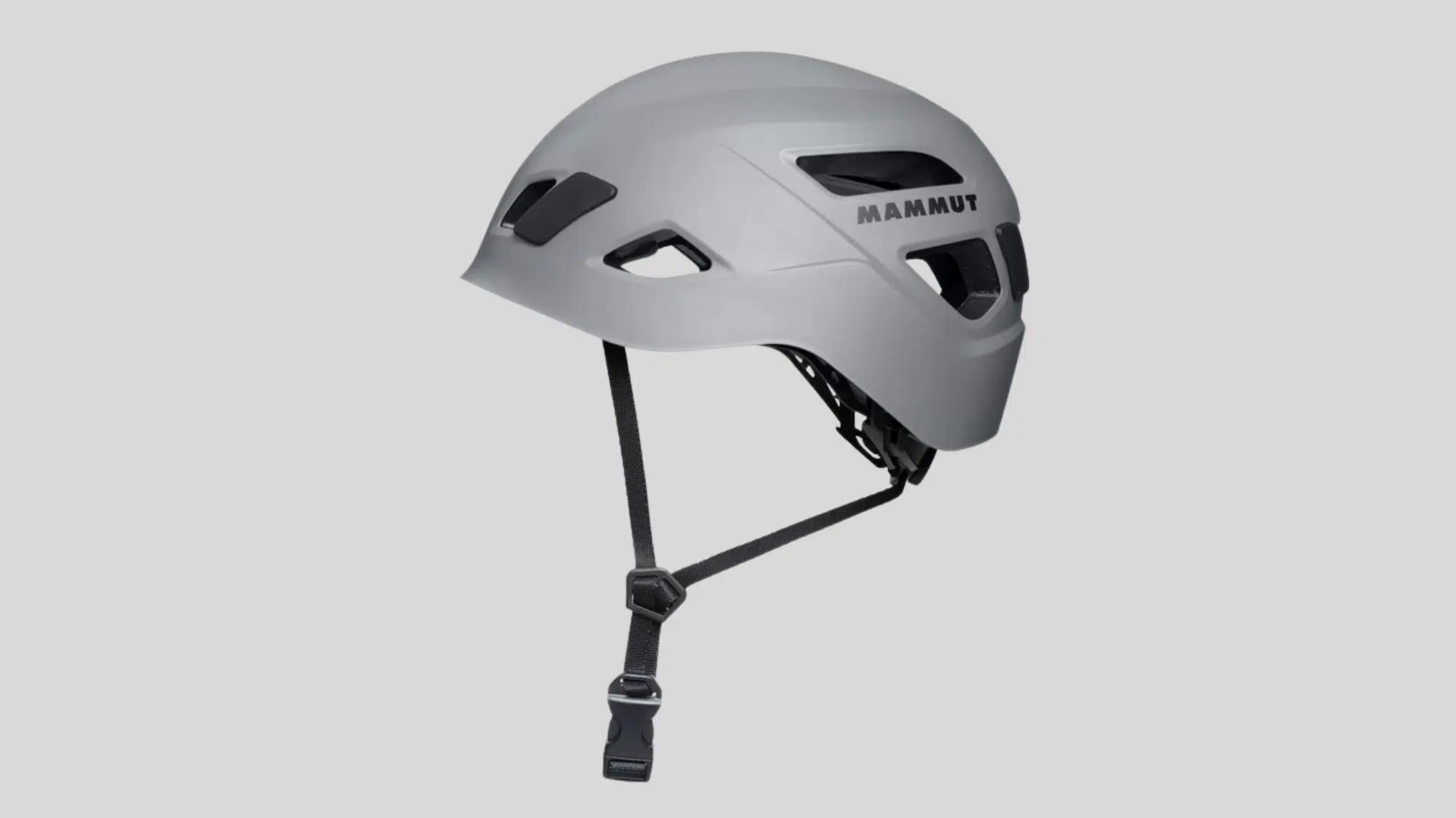 gray climbing helmet with ventilation openings and adjustable chin strap for safety use on a clean background