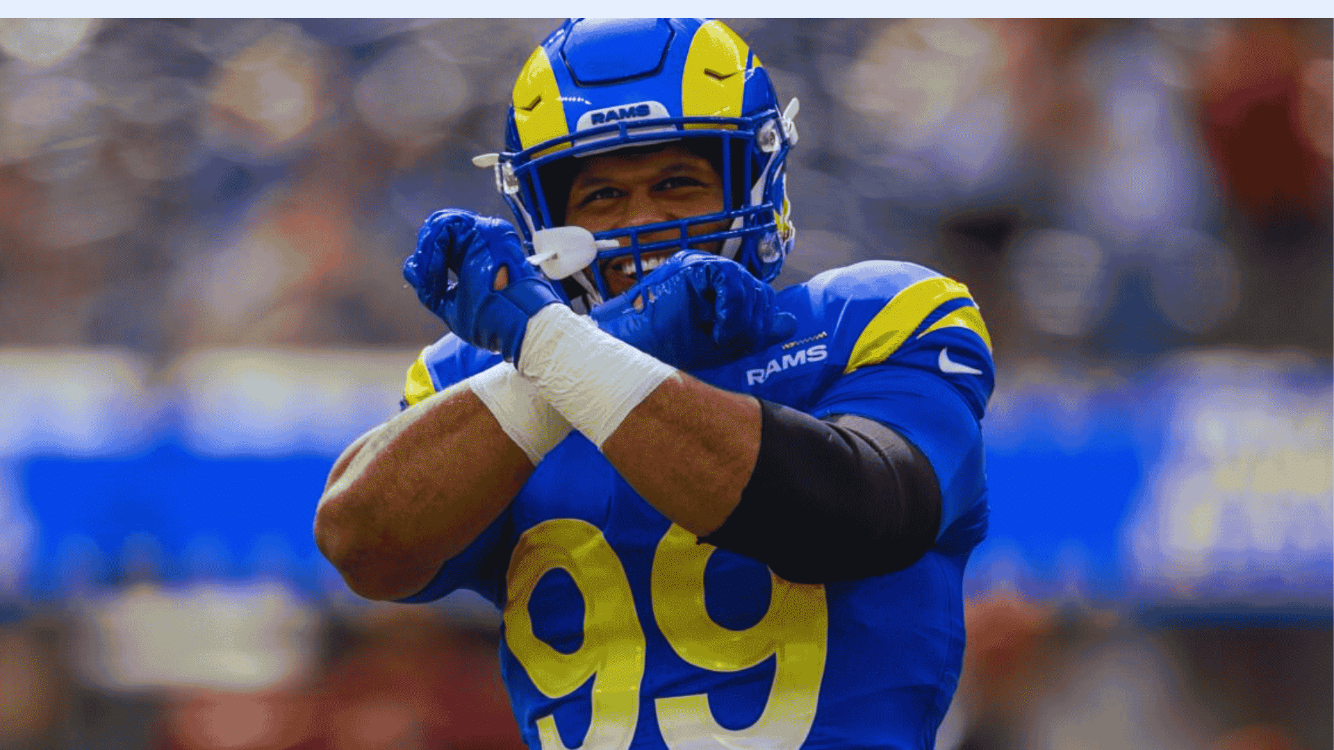 rams defensive player aaron donald wearing number 99 crosses his arms while celebrating during a game