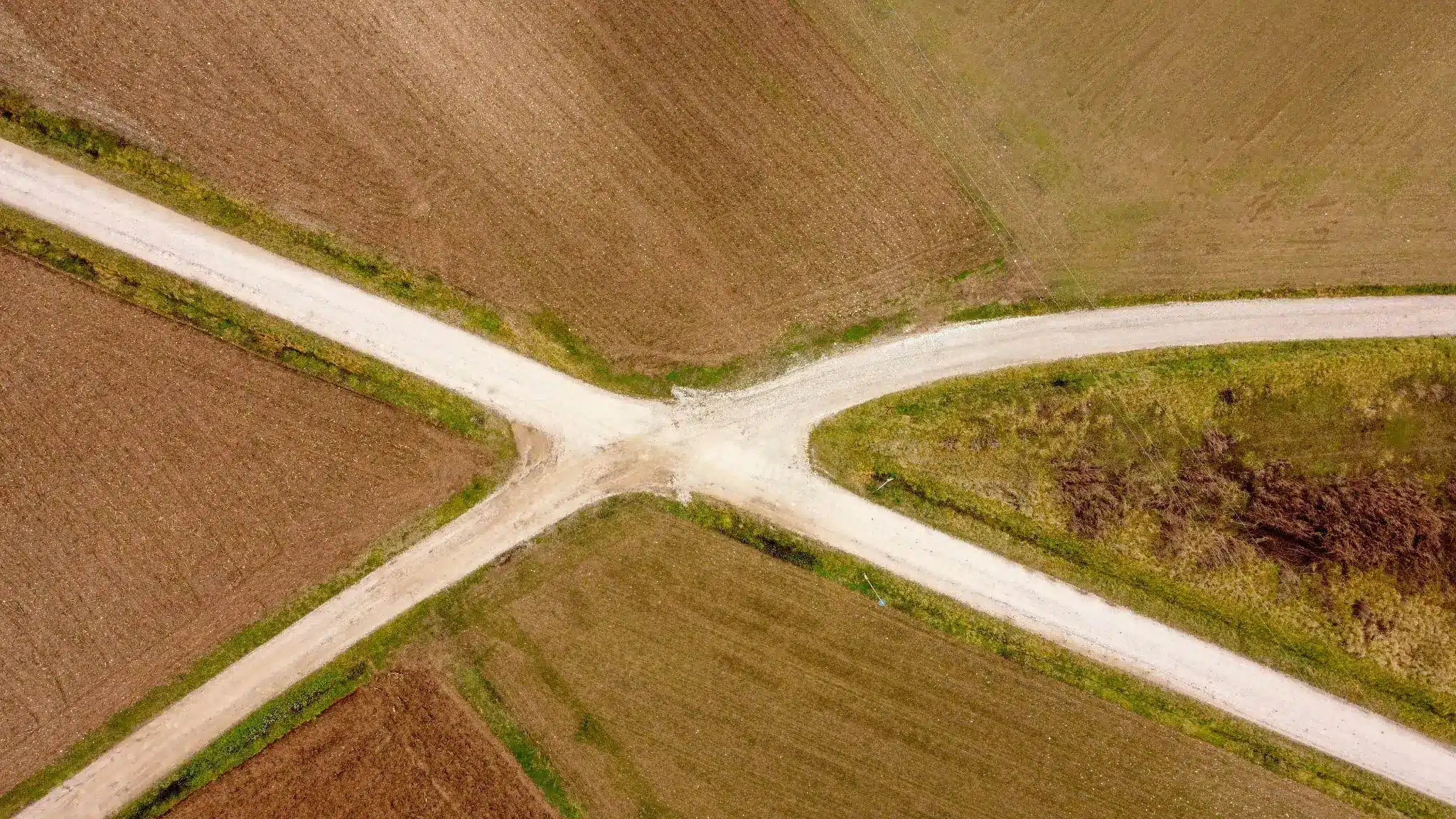 Dirt crossroads intersecting agricultural fields in a rural landscape, viewed from above