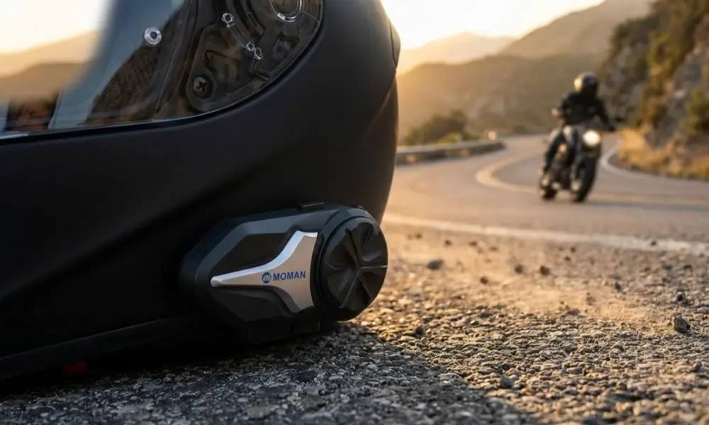 Black motorcycle helmet with attached communication device on asphalt, winding road in background