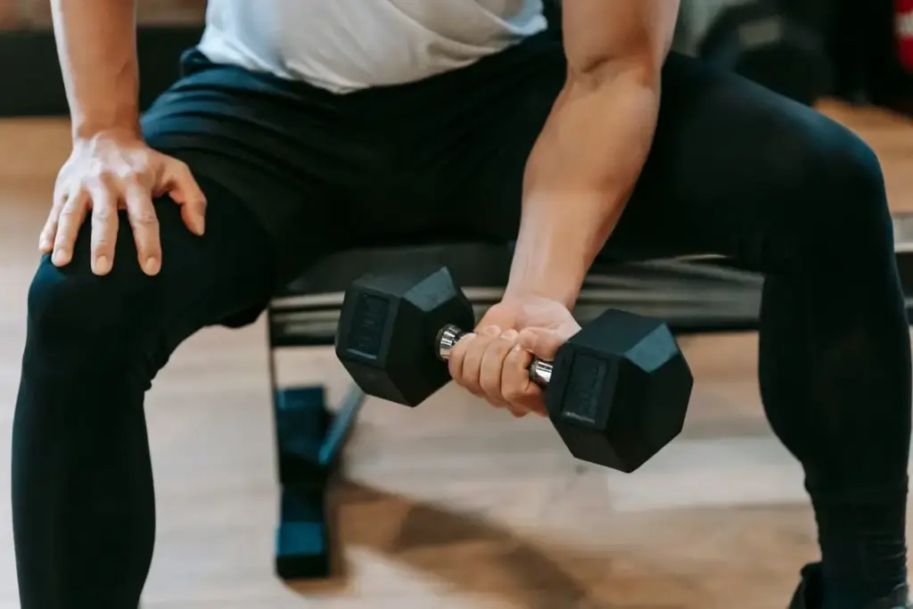 Man lifting dumbbell while seated on bench in gym setting